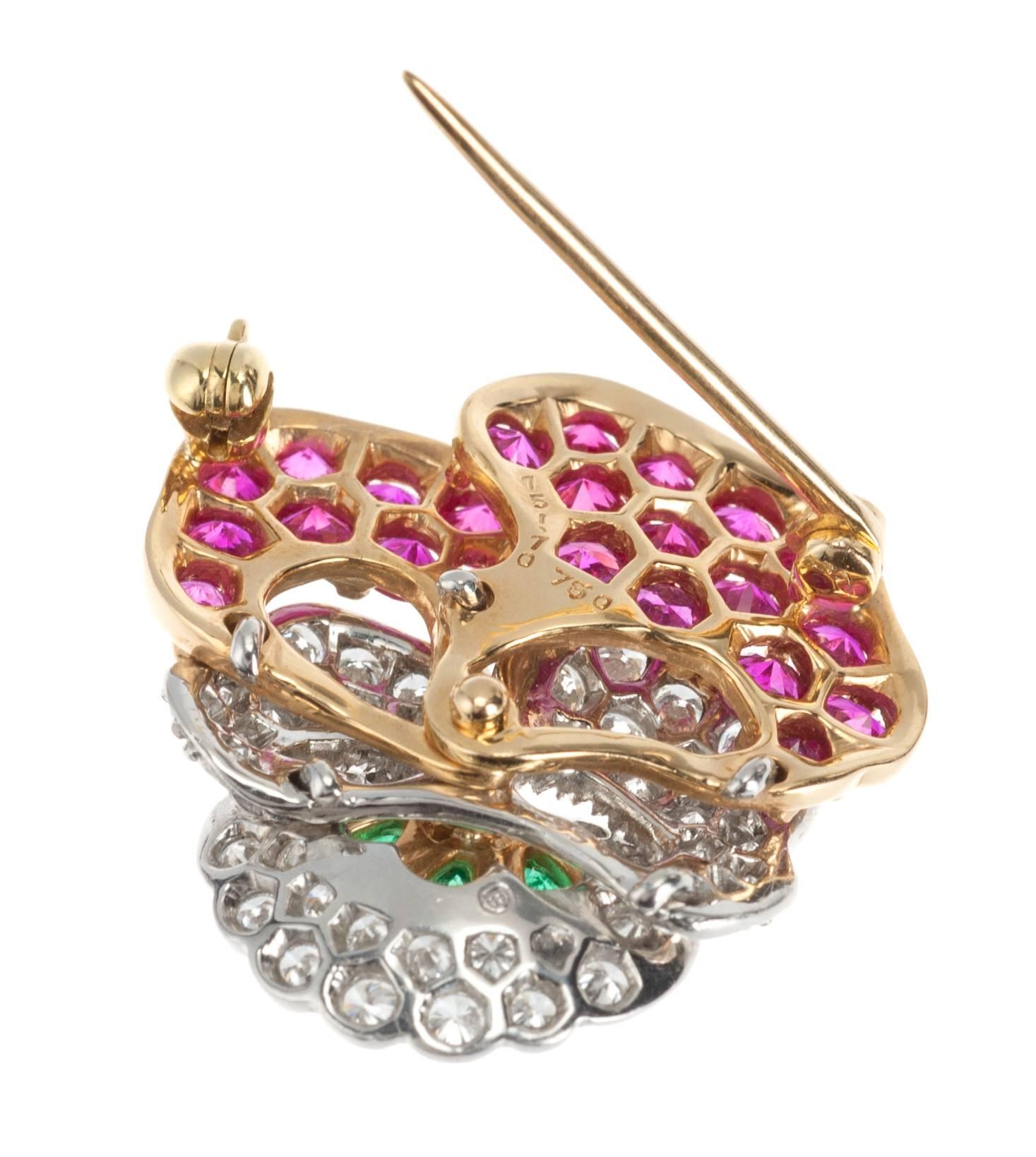 An Oscar Heyman signature pansy brooch in 18-karat yellow gold and platinum is set with 50 brilliant-cut round diamonds, 1.45ctw. of  F-G color and VVS-VS clarity, 23 round pink sapphires, 2.73ctw., and three pear-shaped emeralds, .44ctw. 