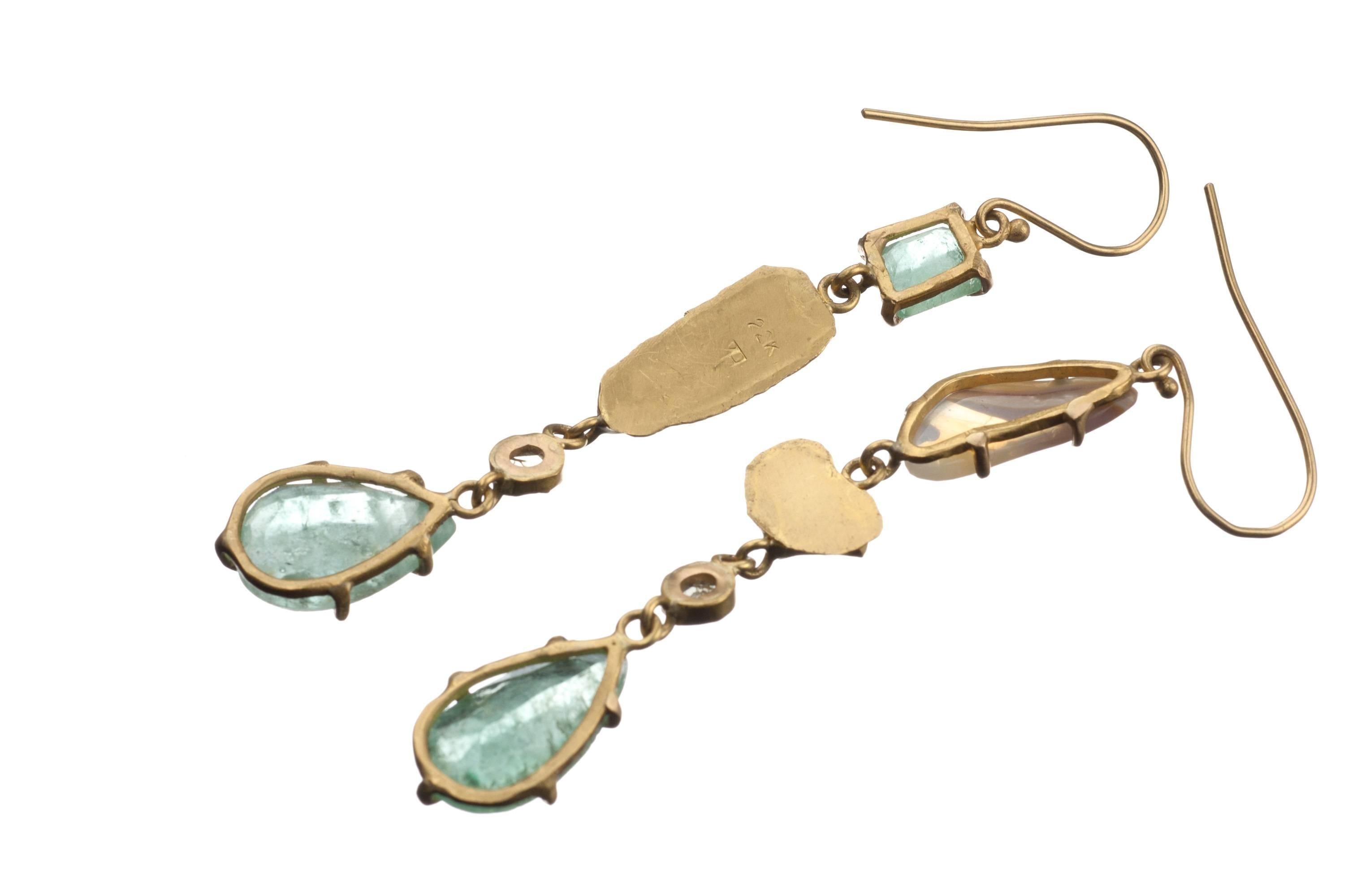 Drop earrings handmade from recycled 22-karat gold by designer Margery Hirschey feature an asymmetric mix of enchanting gemstones. Pear- and emerald-cut emeralds and boulder opals are set in prong and bezel mountings and are finished with two