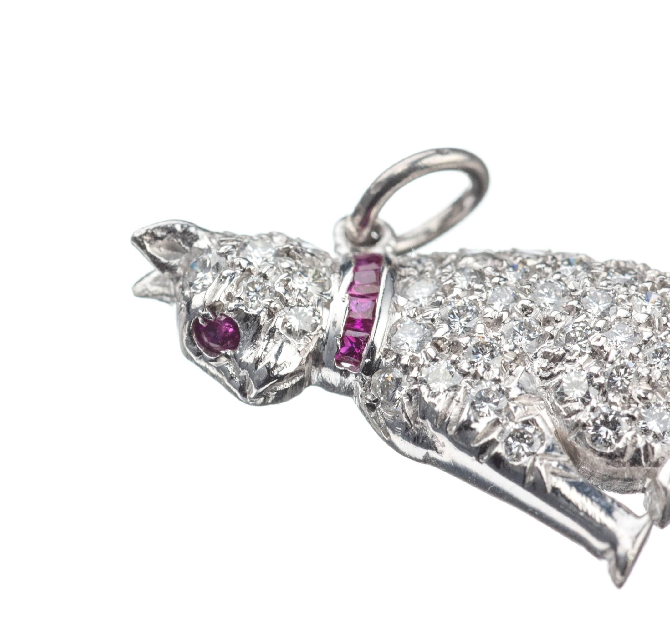 An adorable platinum cat charm is set with 41 brilliant-cut round diamonds, .39ctw., four calibre-cut rubies set into the collar and one round ruby for the eye, .06ctw. Diamonds are of F-G color and VS2-SI1 clarity. Can be worn as a pendant or on a