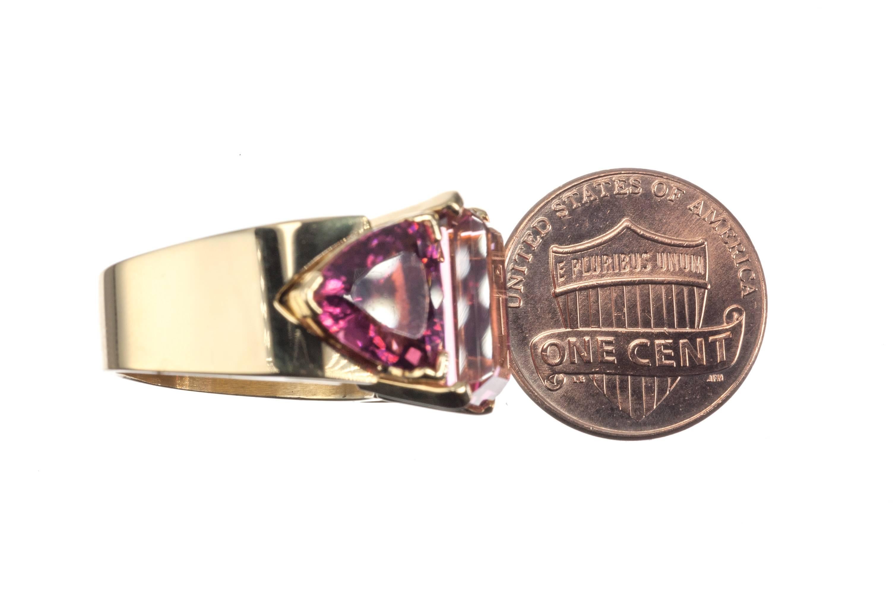 An audacious combination of form and color, this 18-karat yellow gold ring from designer Jean-François Albert is set with one emerald-cut pink tourmaline, 7.49ct., and two trilliant-cut red tourmalines, 5.80ctw. Size 6.5; can be sized.