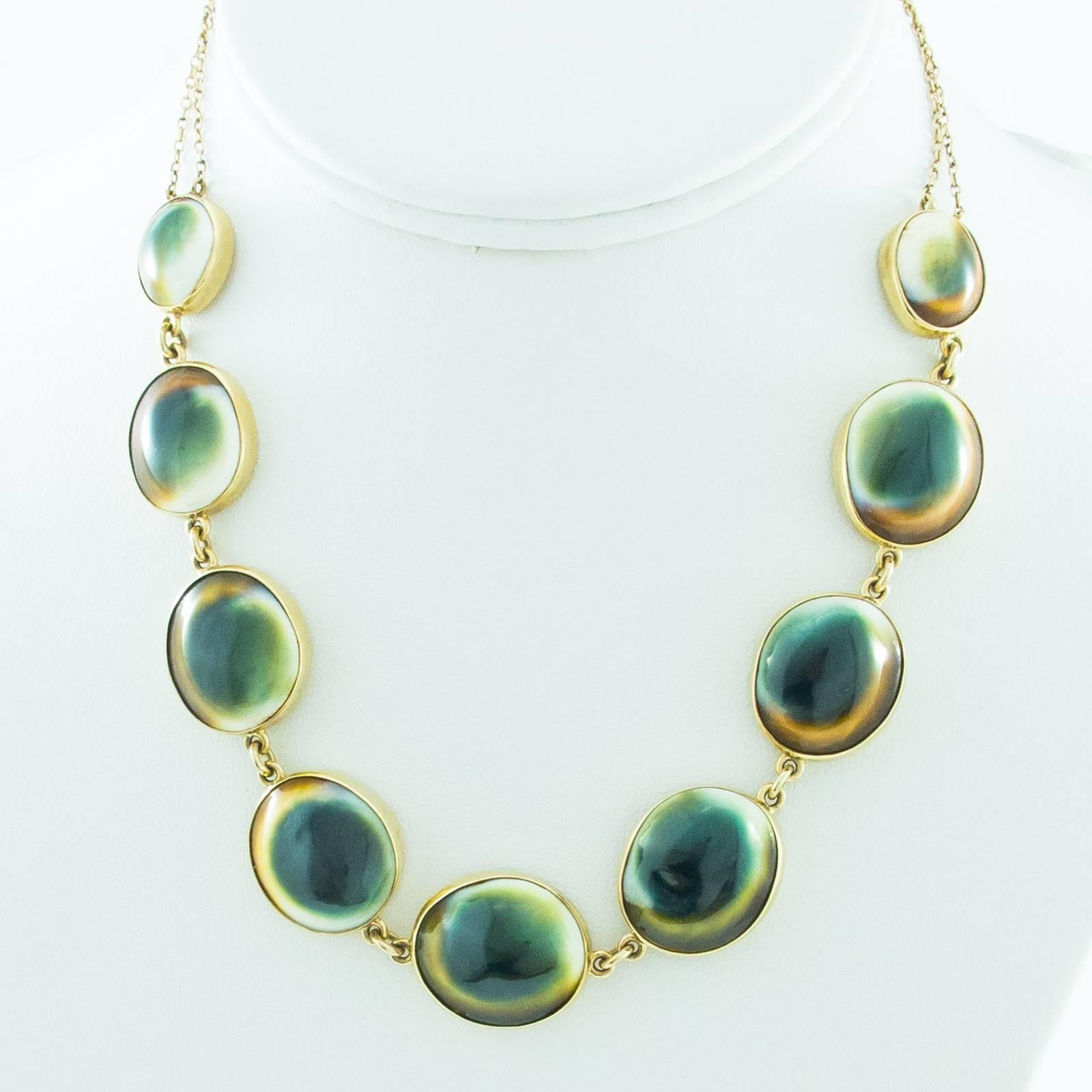 A beautiful necklace comprised of 9 large, graduating Operculum Shells collet set in 9 carat gold suspended from a matching double strand gold chain.

The shells exhibit colors of green to orange on a white ground with the centers  looking somewhat