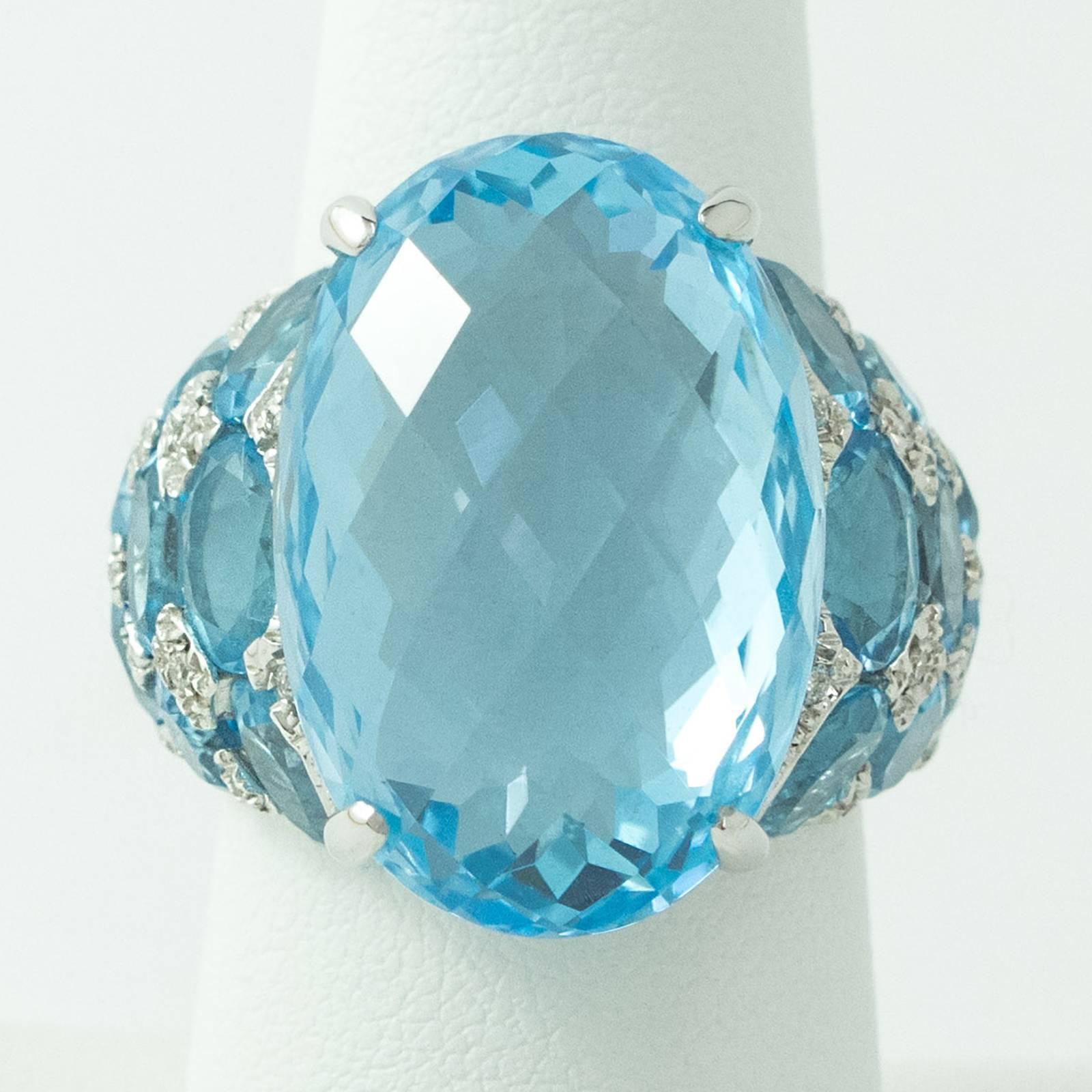 A dramatic Blue Topaz and Diamond White Gold Ring. This large 18K white gold ring is prong set with one Oval cut Blue Topaz measuring 22.20mm north to south and rising10.00 mm up off the top of the finger. The sides are further set with sixteen