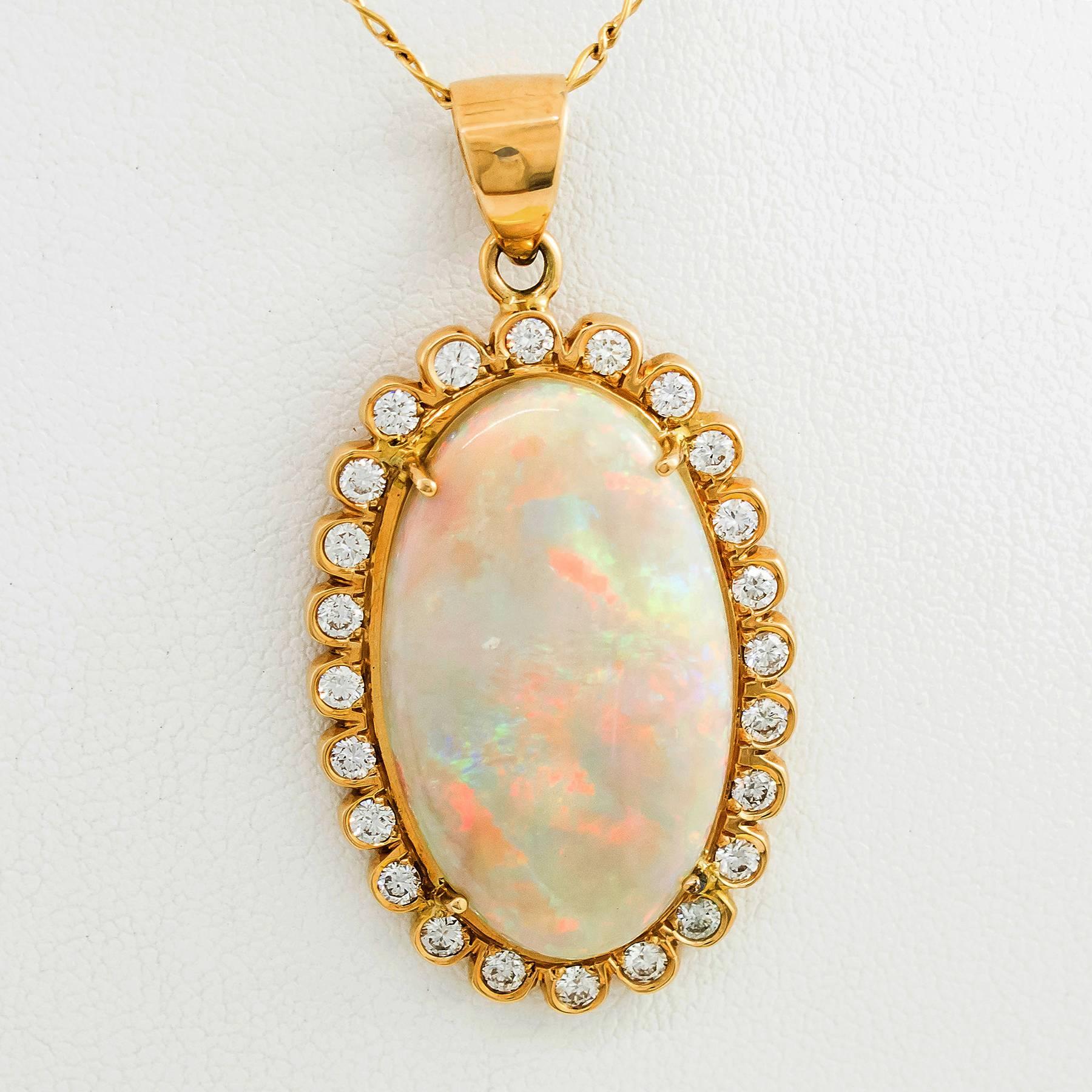 A spectacular Australian Crystal Opal, Diamond and Gold Necklace. This fine cabochon cut oval Opal pendant displays flashing colors of vibrant  reds, greens and blues on a white background.  The Opal is set in a surround of 24 round, brilliant cut