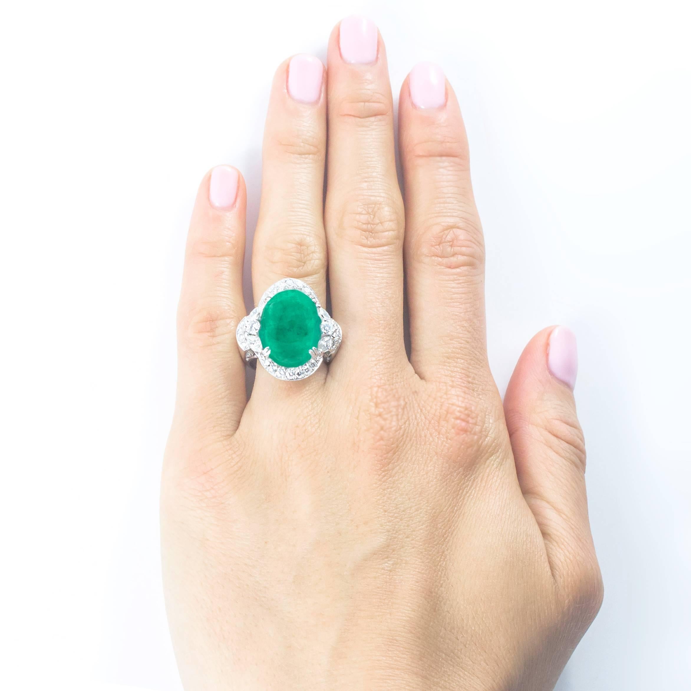 A gorgeous cabochon cut Columbian Emerald measuring approximately  17.70mm x 12.30mm x 7mm, weighing 10.80 carats is set with a diamond surround, in a beautiful, hand crafted 18 Karat white gold mount. 

The Emerald is flanked by 6 large marquise