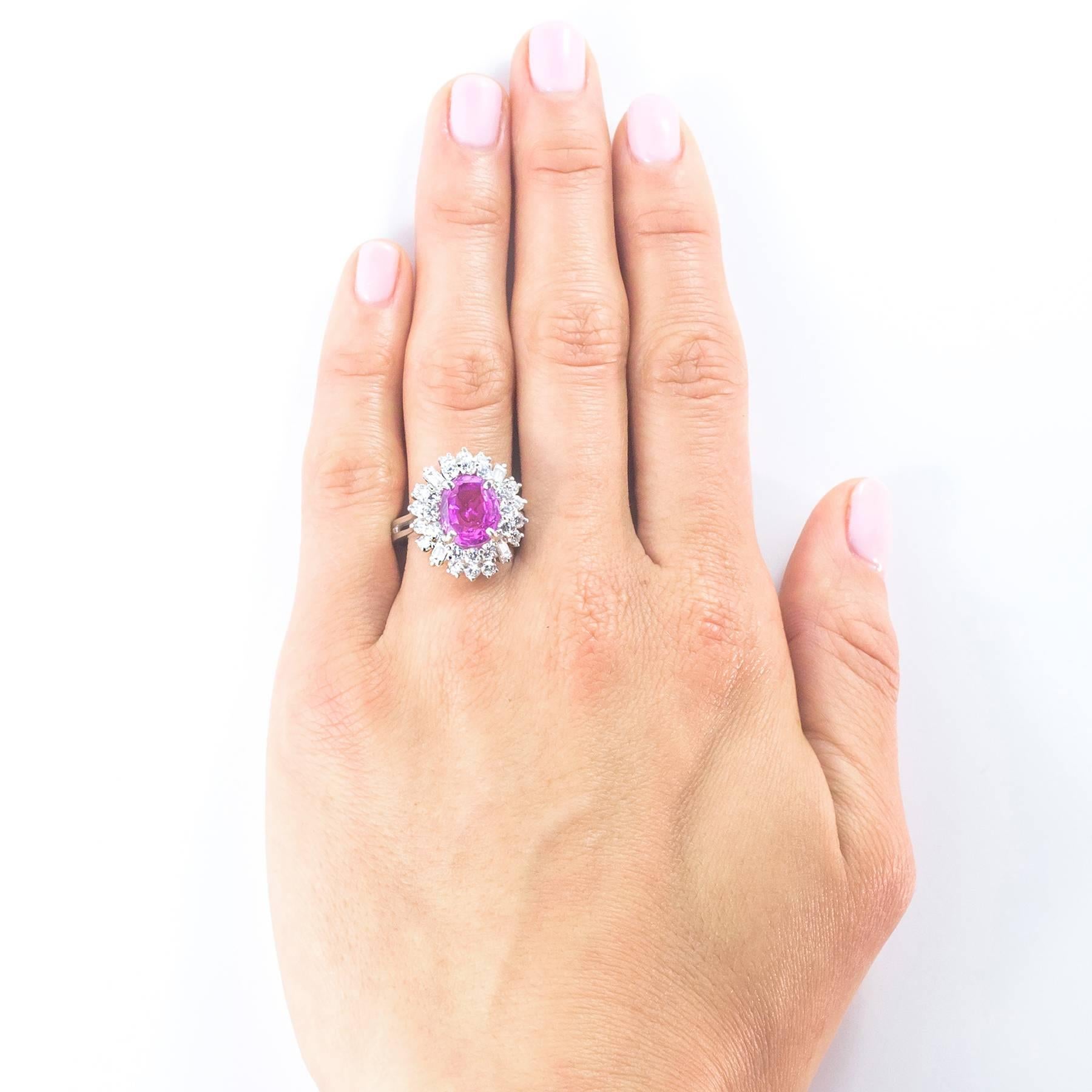 A fine 3.20 carat natural intense Pink Sapphire is oval cut and center set in this gorgeous cluster ring.  The 30 Diamond surround totals 1.52 carats of VVS, F-G Fancy and Round, Brilliant Cut stones. The four Fancy Cut Baguette Diamonds add a