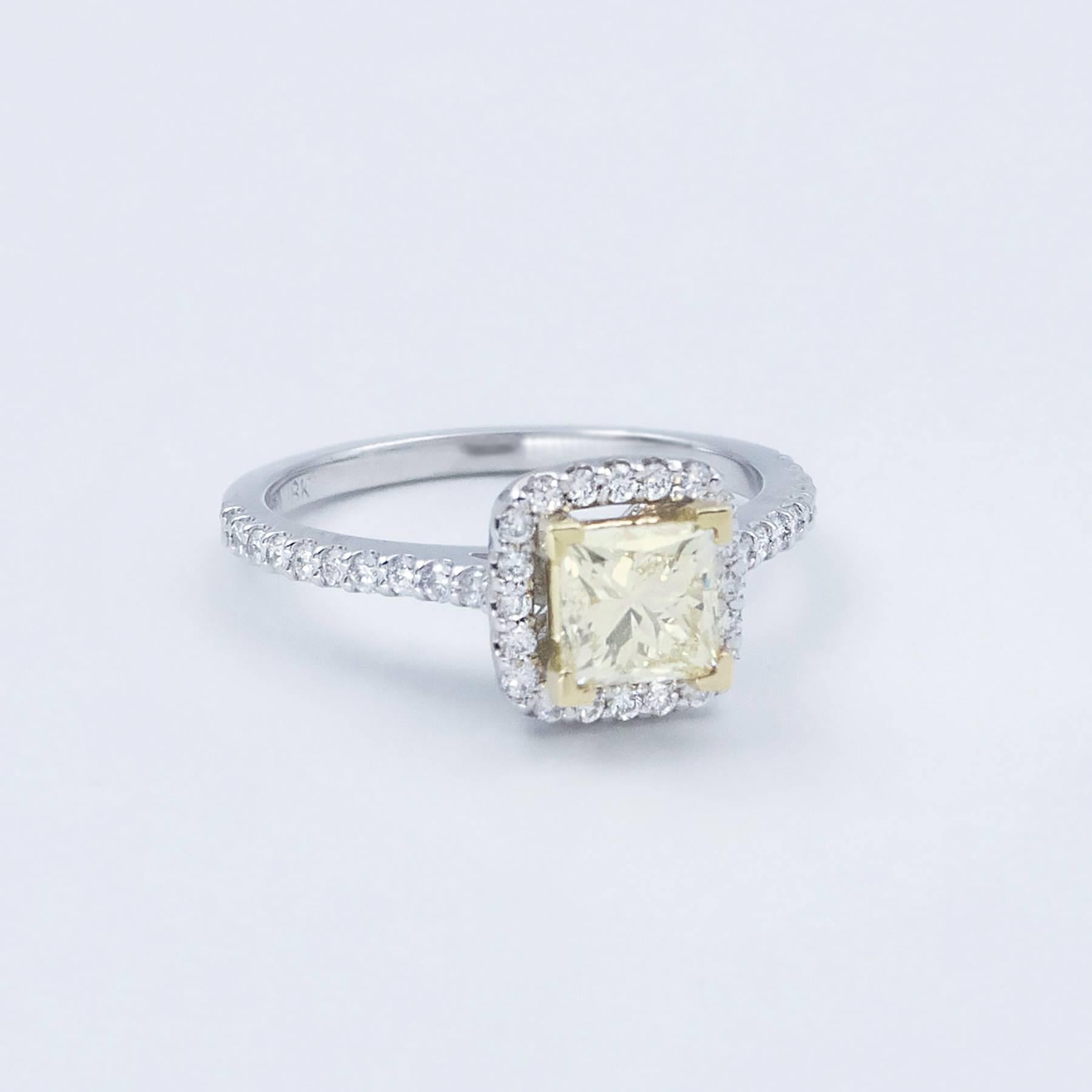 The natural Fancy Light Yellow Princess Cut central Diamond is rated VS2 and weighs 1.02 carats.  Surrounding the center stone are 40 Round, bead set Brilliant Cut White Diamonds that continue to run down the sides of the shank. The small Diamonds