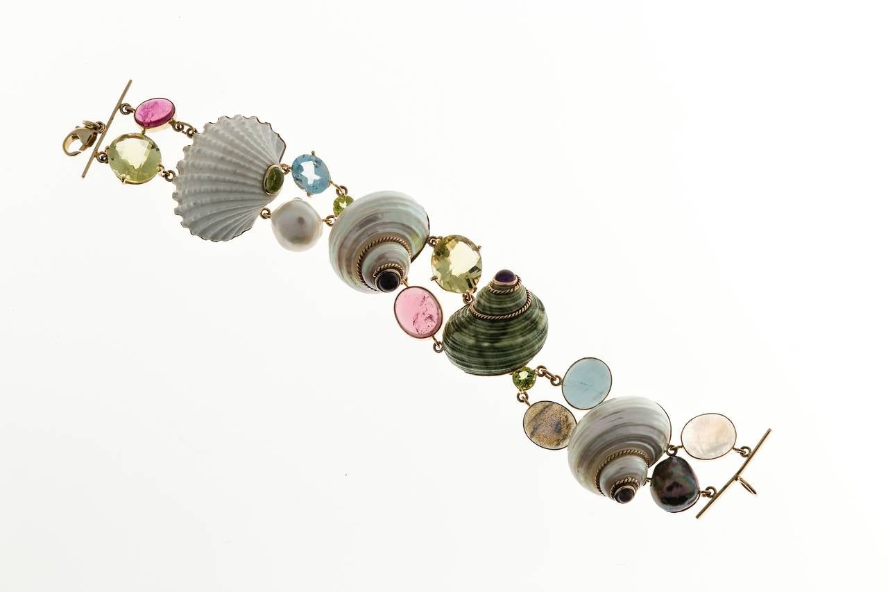 Well-made artistic and beautiful shell and gemstone handmade bracelet.

4 Assorted Shells 25mm wide
2 14 x 11 Citrine yellowish green
4 3mm Cabochon Iolite Amethyst and peridot
2 12mm Baroque Pearls white and black
2 12x 10 Moonstone
1 12 x10
