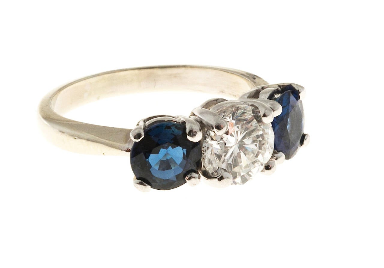 Classic Platinum 3 stone ring set comfortably and low to the finger. Platinum top with 14k shank. The center stone is colorless. Very brightly cut, just under 1.0ct and is matched with 2 incredibly bright, vivid and clear sapphires that are just