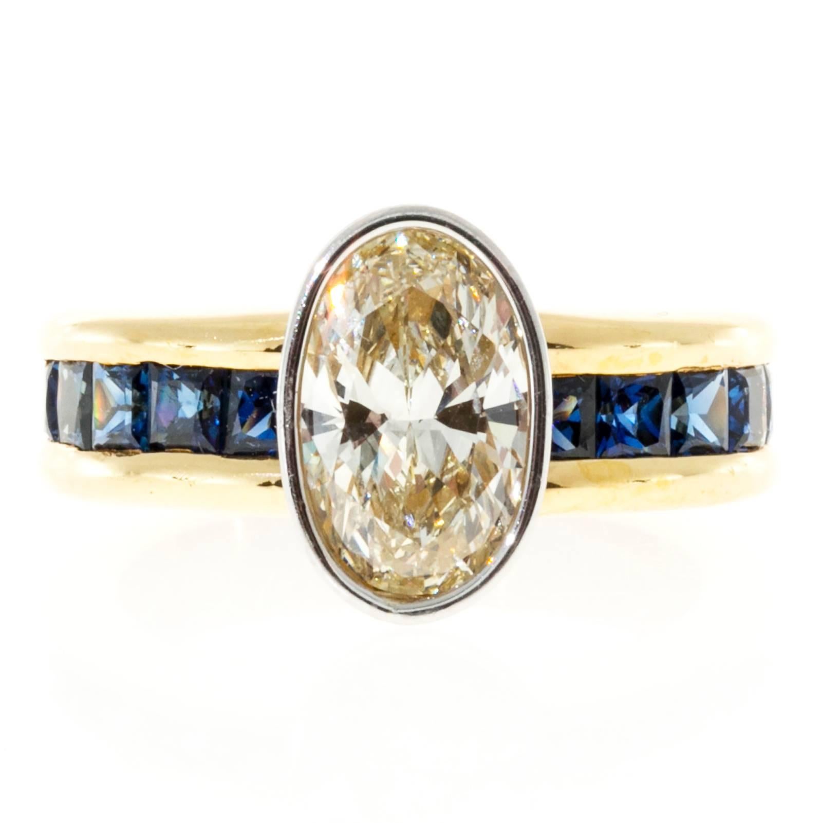 18k yellow gold with vivid blue channel set princess cut sapphires and a Platinum bezel set center oval cut diamond. crt

1 oval diamond 1.67cts, M-N, SI2 measures 10.14 by 6.70mm.
12 Princess cut sapphires approx. total weight 1.50cts
18k