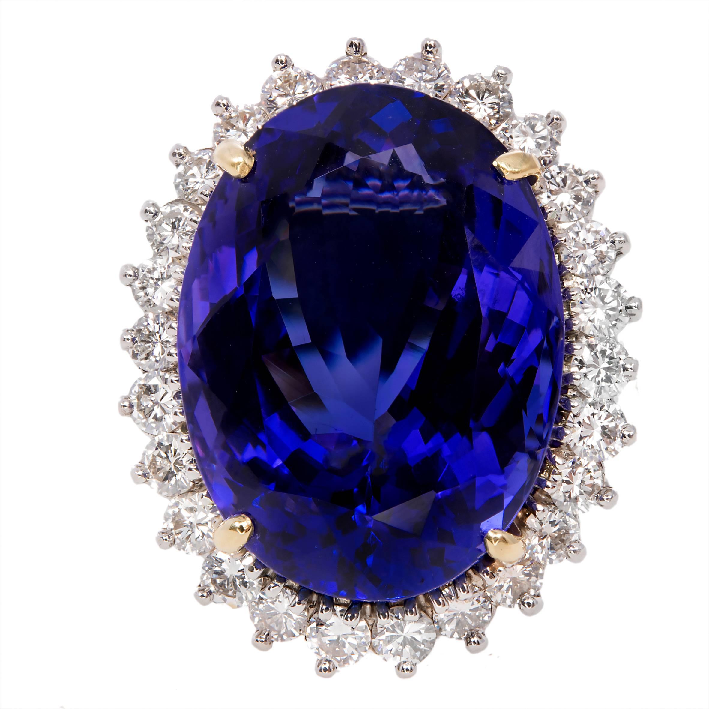 Tanzanite and diamond cocktail ring. 20.51 carat oval blue/purple center stone with a halo of 26 round diamonds in a 18k yellow gold setting.  Circa 1970 

1 oval purplish blue Tanzanite, approx. total weight 20.51cts, VS, 19.98 x 9.5 x 14.7mm
26