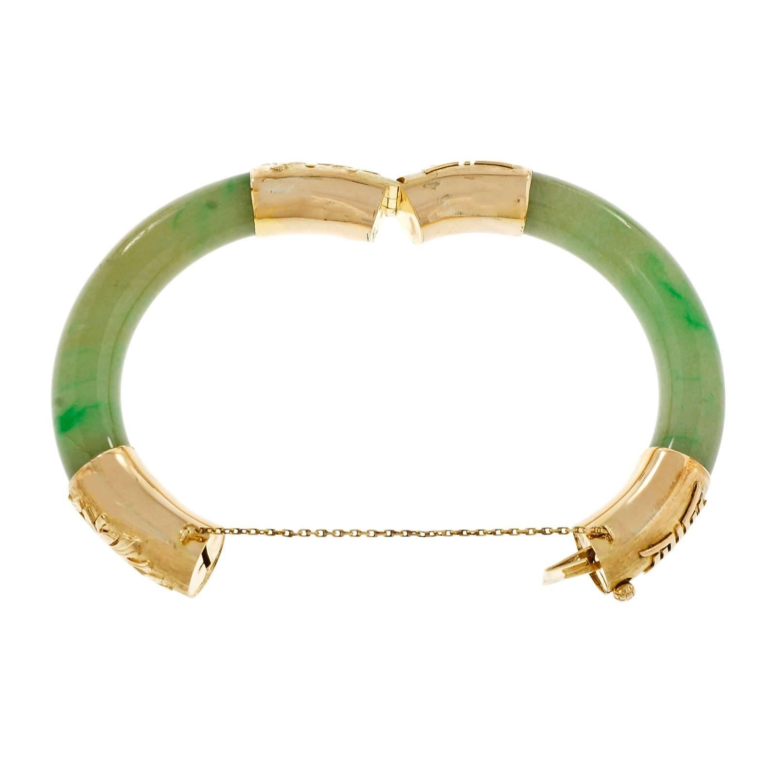 Vintage 11.5mm wide hinged GIA certified natural green Jadeite Jade bangle bracelet, circa 1940. 14k yellow gold detailed hinge caps. Wide translucent Jade sections.

2 Arc shaped mottled green segment of translucent Jadeite Jade, 77.34 x 11.52mm,