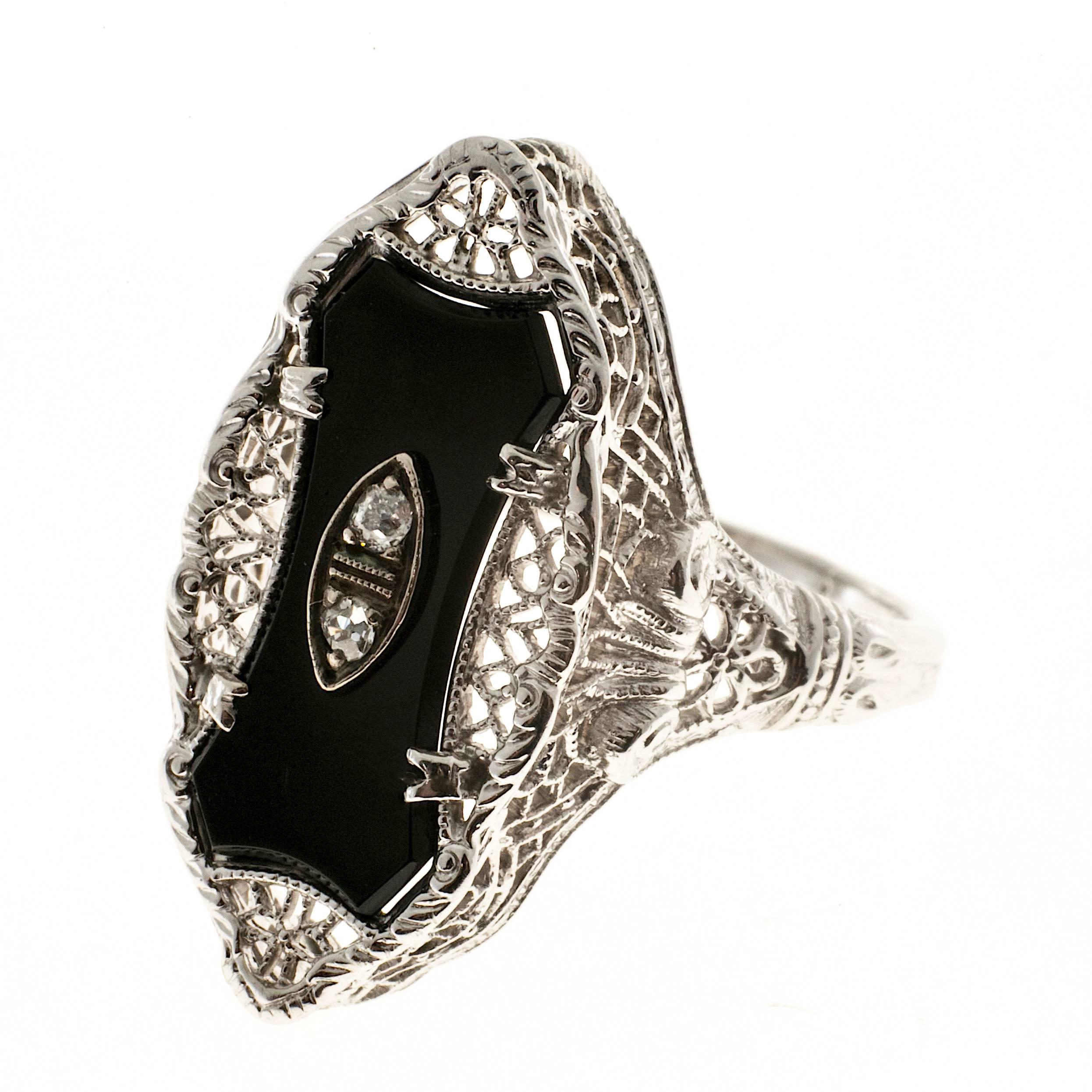 Art Deco filigree ring circa 1930s with custom cut black Onyx and 2 round single cut diamonds in a 14k white gold setting. Pierced tops and sides.

One 16.3 x 7.2mm black custom cut Onyx, approx. total weight 2.00cts, opaque
2 round single cut