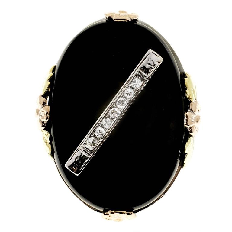Classic filigree 14k white gold ring with pink and yellow gold flowers and jet black Onyx with a white gold diamond center strip. Circa 1930-1940.

7 single cut diamonds, approx. total weight .07cts, G, VS
Black Onyx: 24 x 17mm oval
Size 6 and