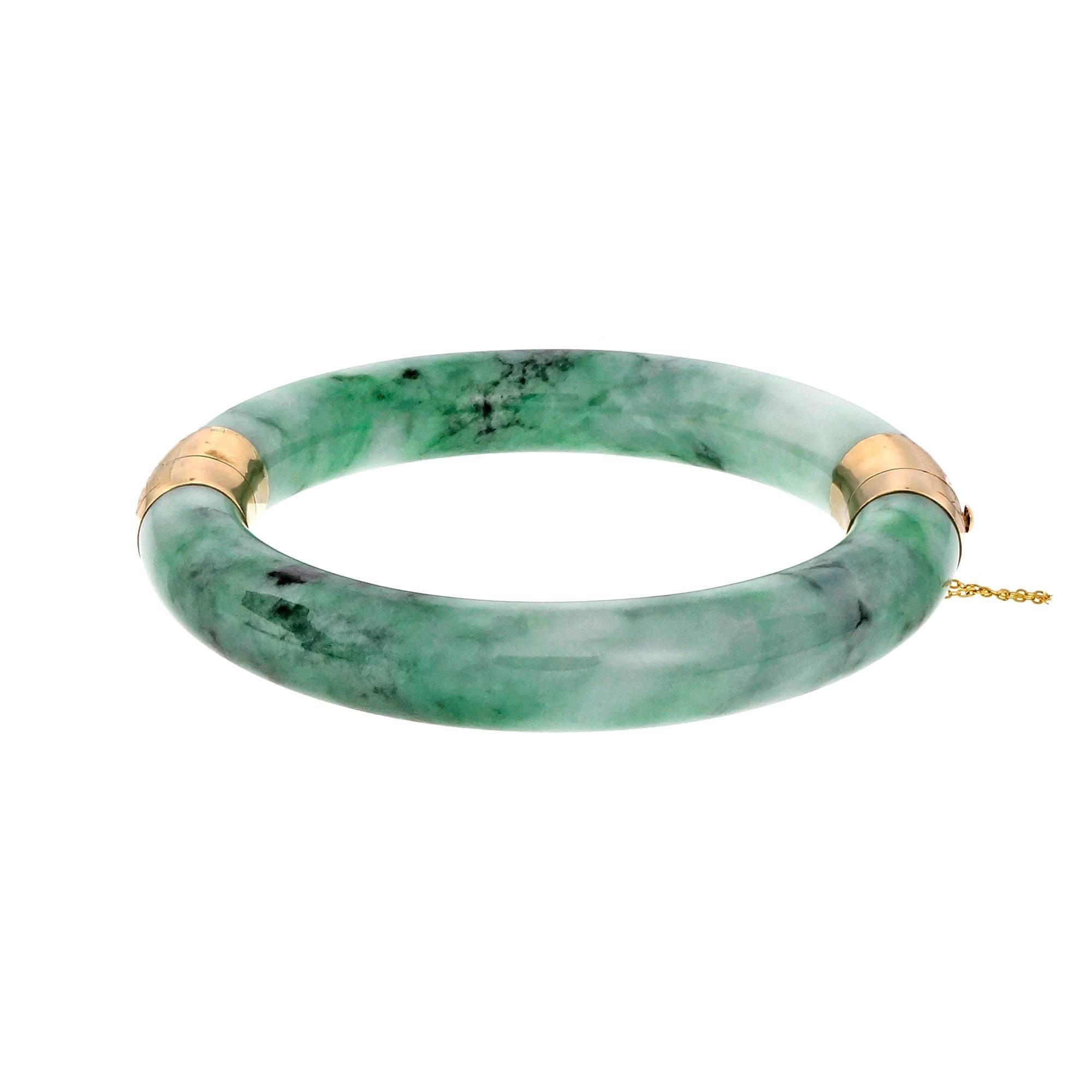 Over-sized hinged Jadeite Jade bright mottled green bangle bracelet with 14k yellow gold hinge catch and safety chain. Goes over a large hand and fits a wrist up to 8.75 inches. GIA certified natural untreated Jadeite Jade.

14k yellow gold
2