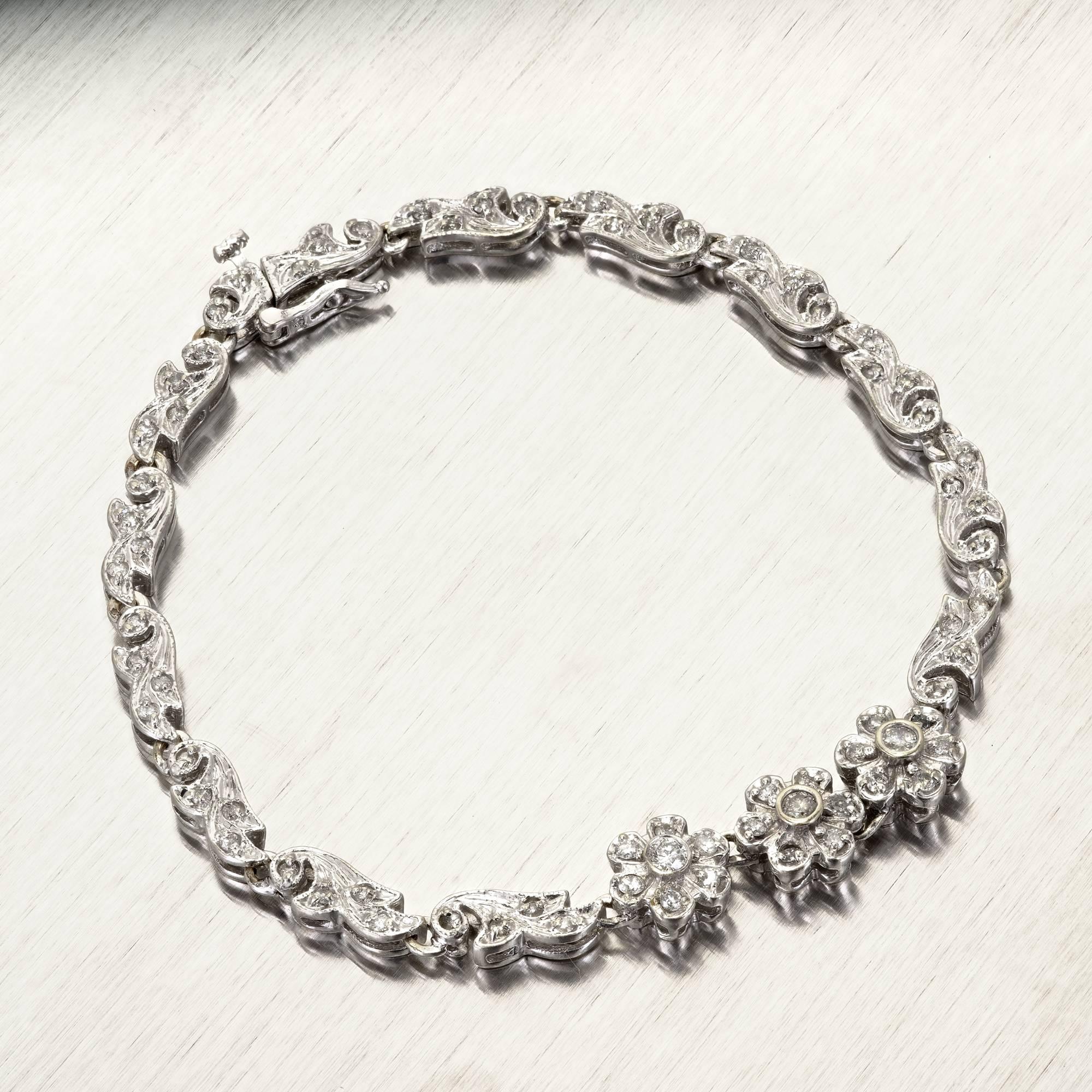 Hinged Swirl link diamond bracelet with flower design in the center. Set with a full cut diamonds. Circa 1960. 

3 round diamonds I SI-J Approximate total carat .12cts
70 round diamonds I SI-J Approximate total carat .56cts
12.2 grams
14k White