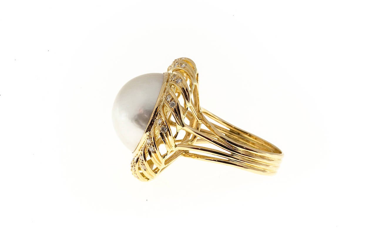 Pearl and diamond cocktail ring. Handmade wire frame swirl ring with a fine natural silvery white Mobe pearl with a diamond halo setin 18k yellow gold.

48 full cut diamonds, approx. total weight .85cts, F, VS
Natural color silvery white high luster