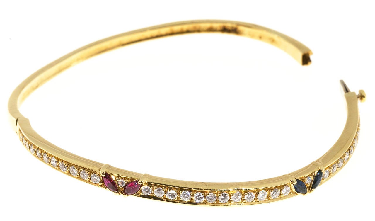Hinged oval 18k Ruby Sapphire Diamond bangle bracelet

2 Marquise Sapphires, approx. total weight .20cts
2 Marquise Rubies, approx. total weight .20cts
36 full cut diamonds, approx. total weight .58cts, F, VS
Tested: 18k yellow gold
14.6