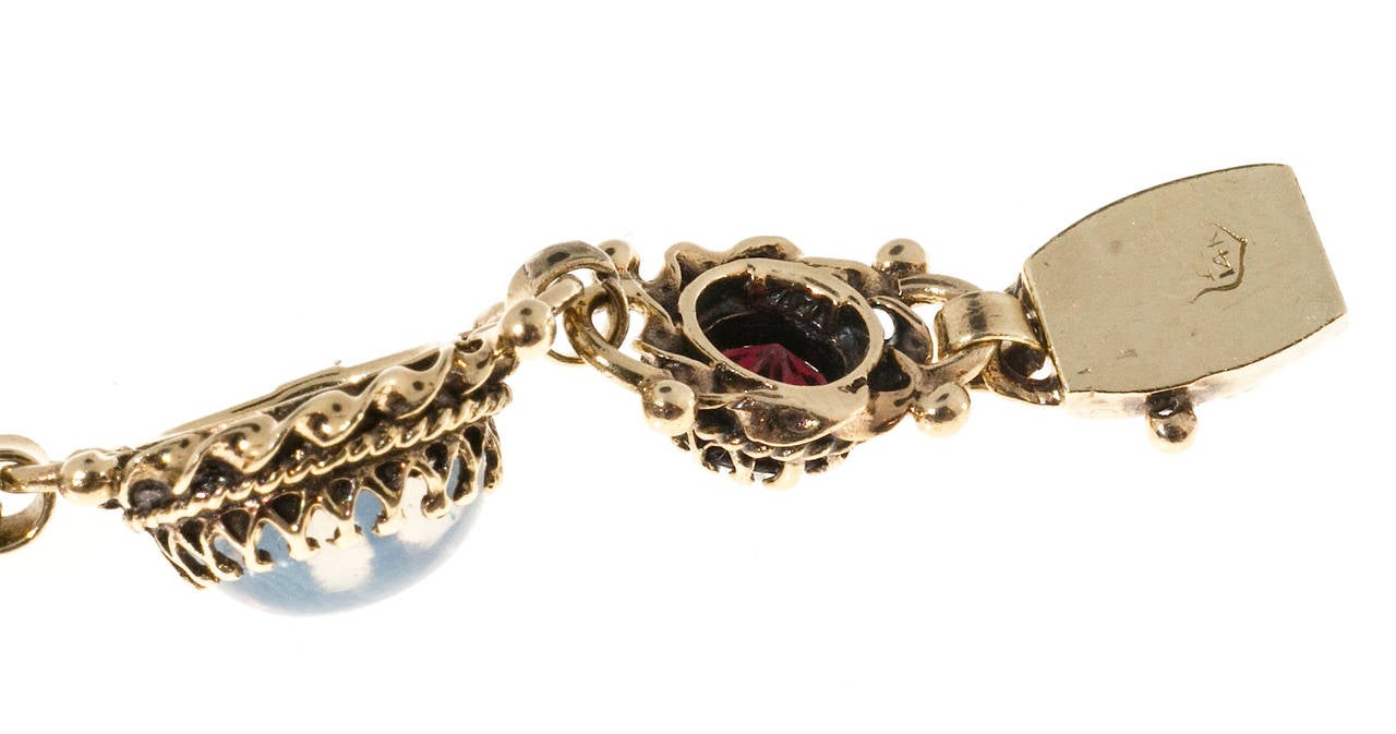 Victorian revival 14k yellow gold bracelet with genuine Garnet and beautiful wispy blue moonstones. Circa 1930 to 1940.

4 9 x 7mm oval cabochon bluish genuine Moonstones, approx. total weight 7.0cts
5  5mm reddish brown genuine Garnets approx.