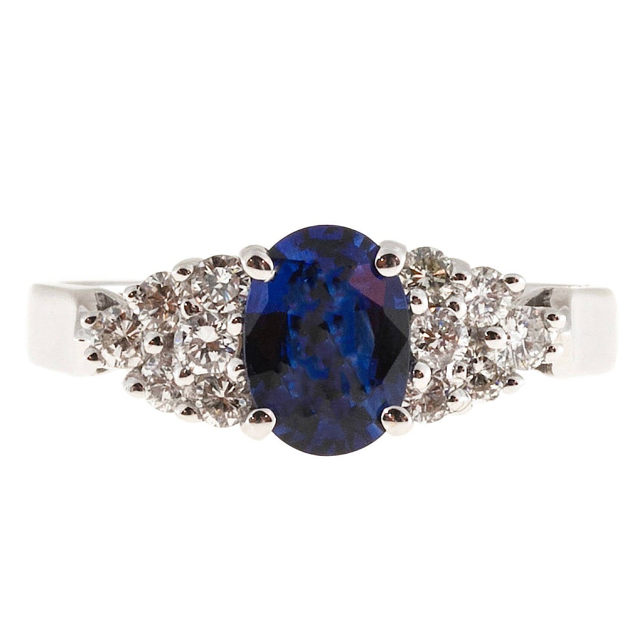 Blue oval Sapphire and round diamond engagement ring in a 18k white gold setting

1 oval bright blue Sapphire, approx. total weight 1.00cts, 7 x 5mm. Super bright blue, some color zoning
12 full cut diamonds, approx. total weight .36cts, F, SI1
Size