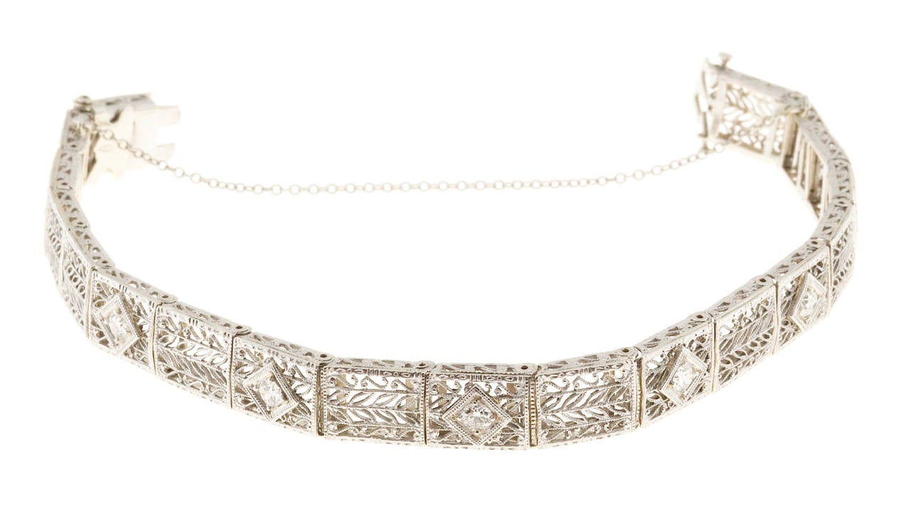 1935 Beautiful 8mm wide pierced hinged link filigree  white gold and platinum bracelet with safety chain and underside safety. The bracelet is set with 5 transitional cut diamonds .16cts each hand set in white gold boxes. Filigree hand pierced tops