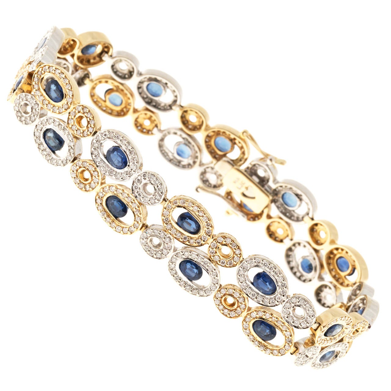Sapphire and diamond gold link bracelet. 24 cornflower blue oval sapphires each with a halo of full cut diamonds. 14k yellow and white gold alternating links. Designer BJC. Hidden box catch double side lock safety. 7.5 inches in length. 

24 genuine