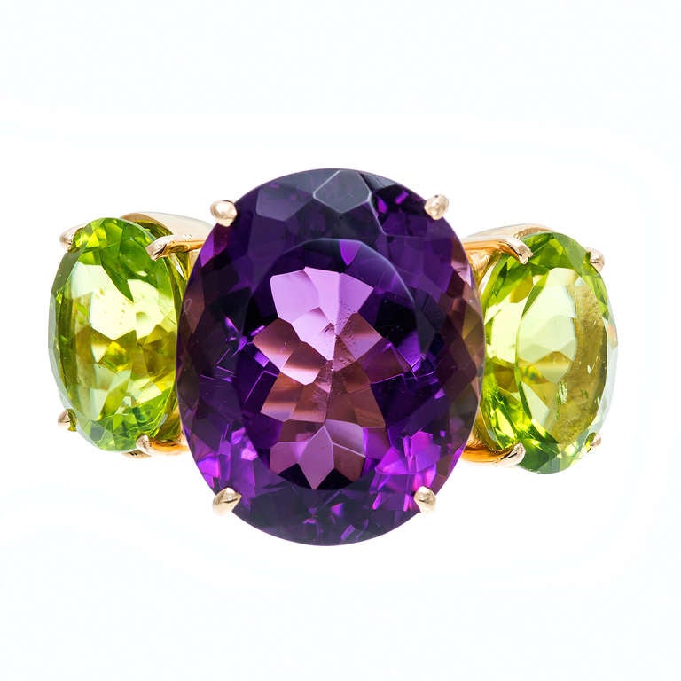 Substantial heavy solid 18k yellow gold ring with bright well polished genuine Amethyst and Peridot. We cannot quite read the markers mark. Looks great on the hand.

18k Yellow gold 
One bright purple oval Amethyst, approx. total weight 11.00cts,