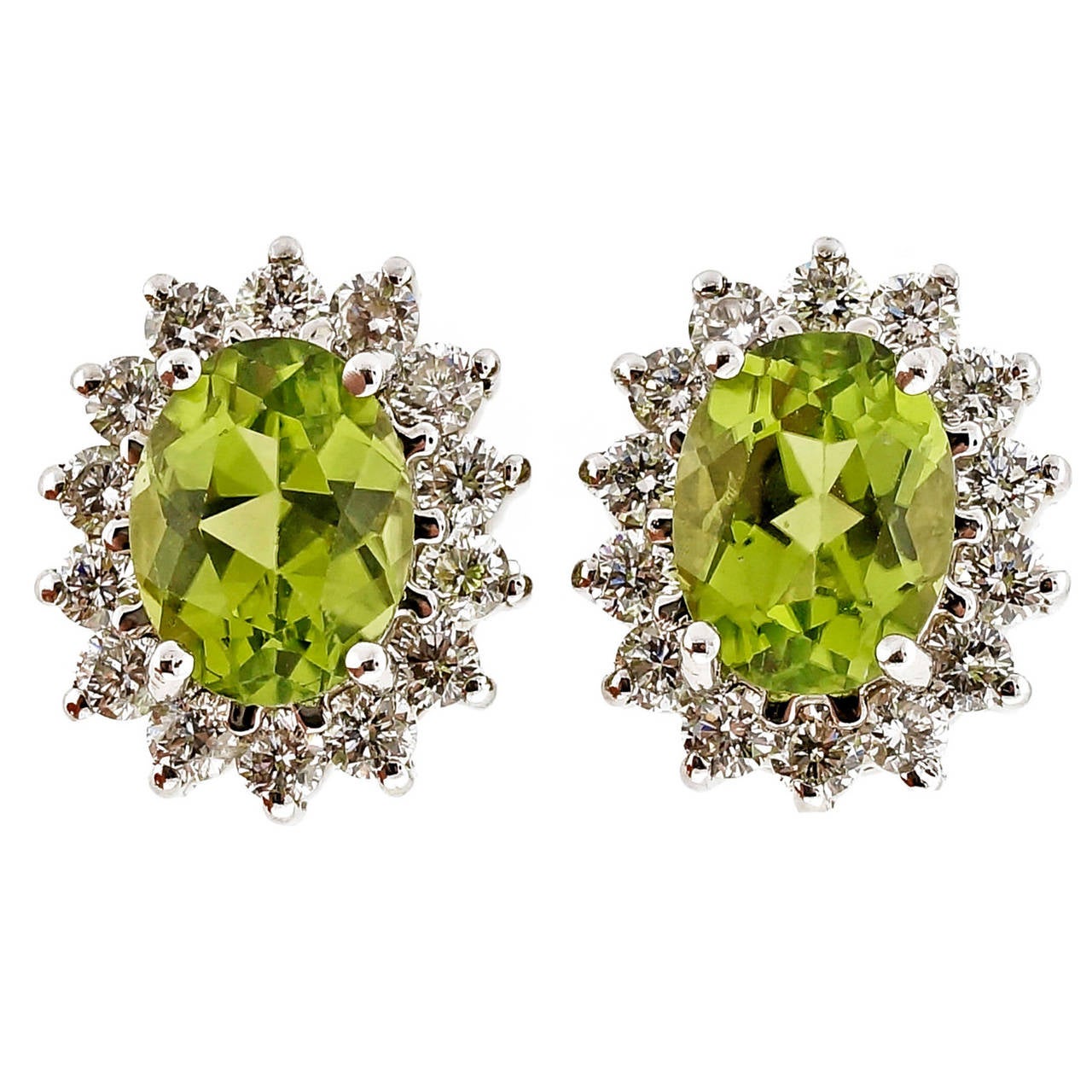 Oval Peridot and diamond halo stud earrings. 2 bright green Peridots accented by round, well cut diamonds.  Circa 1960 -1970.

2 oval bright green Peridot, approx. total weight 2.75cts, 7.90 x 6.10 x 3.81mm
28 round diamonds, approx. total weight