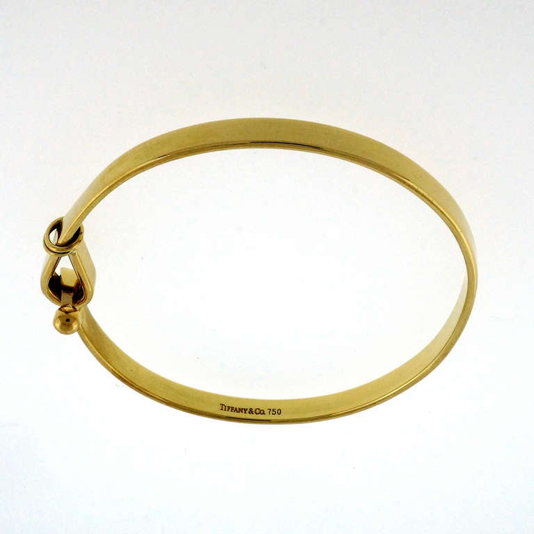 Authentic Tiffany & Co hook and eye style solid 18k yellow gold bangle bracelet. Looks great on the wrist.

18k Yellow gold
Brand: Tiffany & Co  
Width at top: 10.5mm  
Height at top: 7.6mm Width at Bottom: 4.2mm  Fits a standard 7  to 7 1/2
