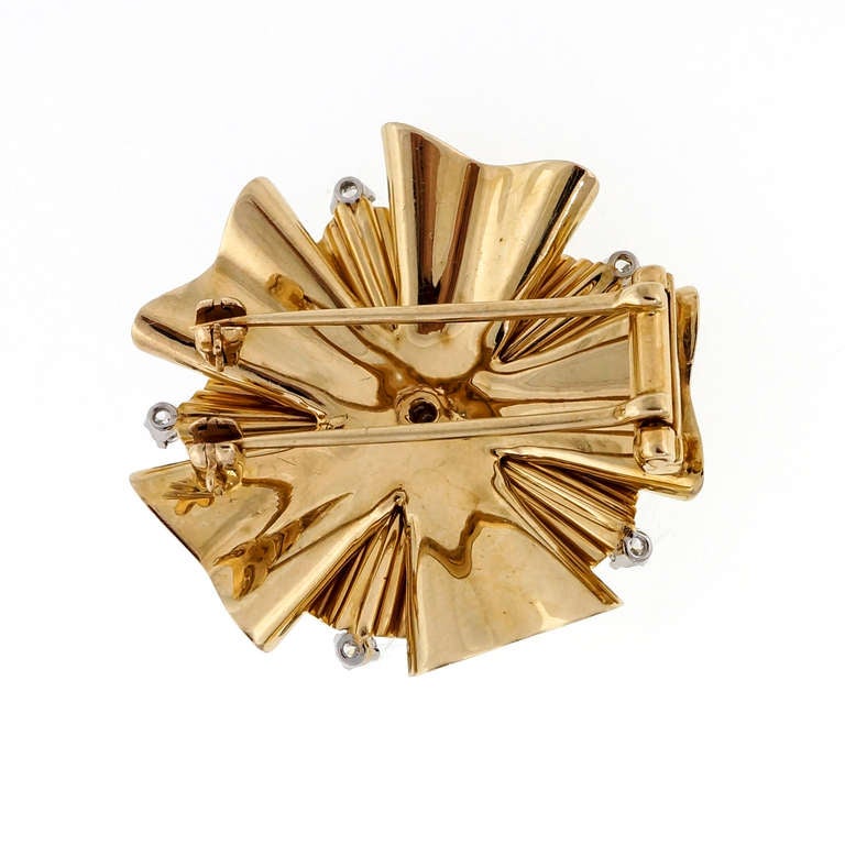 Folded ribbon design 1960 Tiffany & Co brooch pendant. Double pin stem for stability each with its own catch. A chain can fit behind the pin to wear safely as a necklace. 

14k Yellow gold
16 round brilliant cut diamonds, approx. total weight