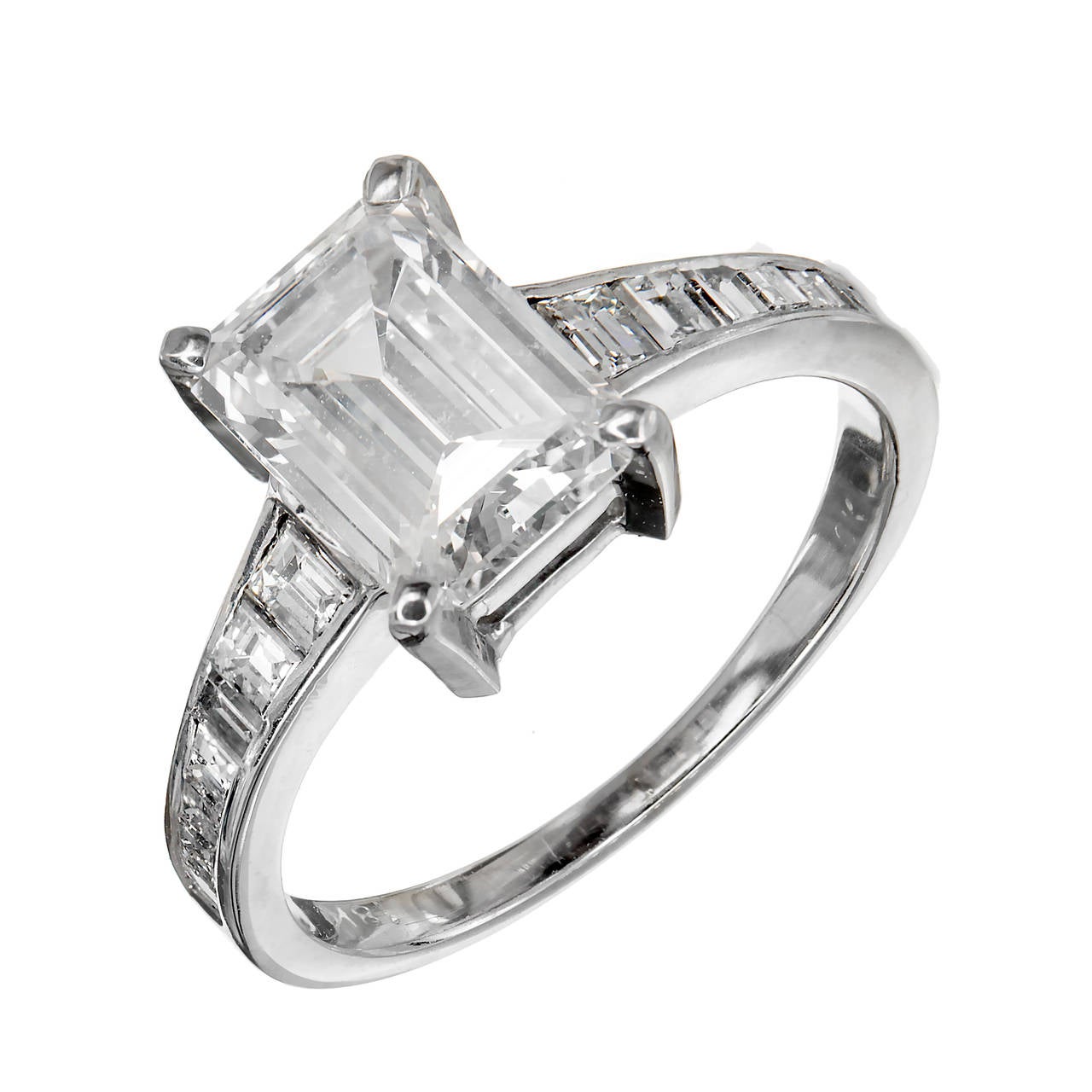 beautiful custom made engagement ring in 18k white gold with custom cut square to trapezoid step cut side diamonds leading up to a sparkly step cut Emerald cut diamond with just a hint of warm color and no visible flaws. Strong blue florescence