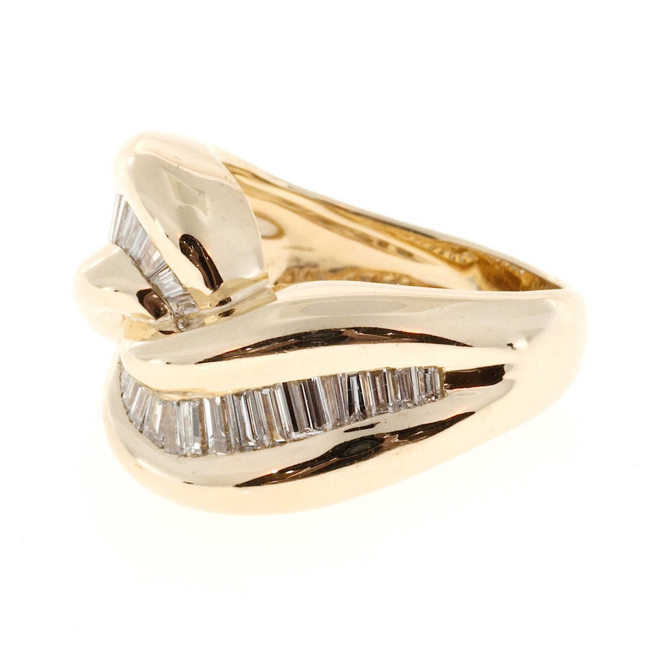 Swirl design 1960 high grade baguette diamond ring. Signed KA, number 4761.

36 baguette diamonds, approx. total weight .70cts, F, VS – SI
14k yellow gold
Tested and stamped: 14k
Hallmark: KA 4761
8.3 grams
Width at top: 14.35mm
Height at