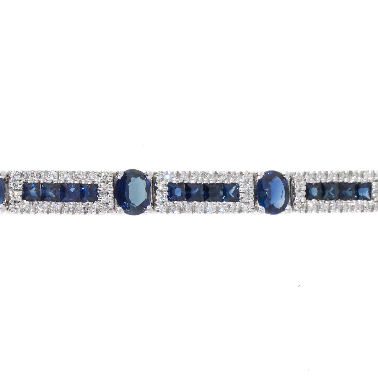 Beautiful hinged link white gold bracelet signed ML set with bright blue square and oval Sapphires and nice diamond accents. Built in hidden catch with double side lock safety. Circa 1970 -1980.

12 oval deep blue Sapphires, approx. total weight