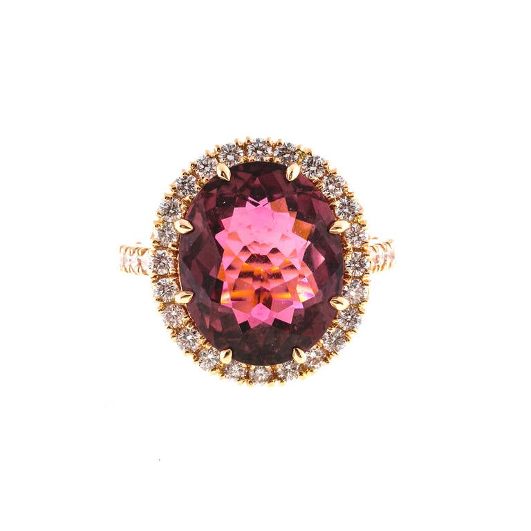 18k rose gold ring with a bright pink oval Tourmaline 8.86ct surrounded by full cut diamonds. 

1 oval pink Tourmaline 15 x 12 x 6.8mm, approx. total weight 8.86cts
32 full cut diamonds, approx. total weight .93cts, F, VS
Stamped: 750 D 0.93