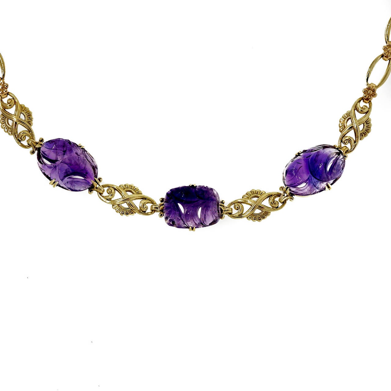 Retro late Art Deco 1940's 14k slightly greenish gold necklace with carved natural untreated Amethyst separated by scroll link sections.

14k yellow gold
3 purple carved translucent Amethyst Quartz, approx. total weight 22.00cts, 17.5 x 12mm,