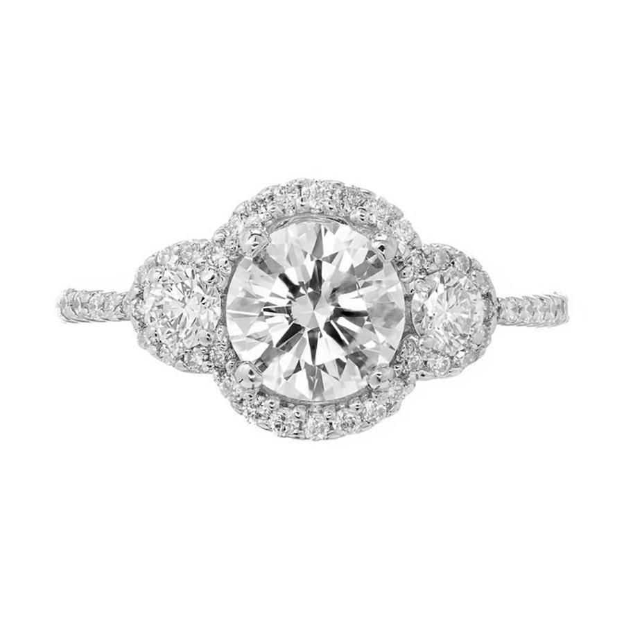 Anello di fidanzamento a tre pietre Halo con diamanti rotondi taglio brillante centrali e laterali in una montatura in oro bianco 18 carati.

1 diamante rotondo taglio brillante, peso totale circa 1,02cts, H. H., SI2, certificato EGL #US64634402D