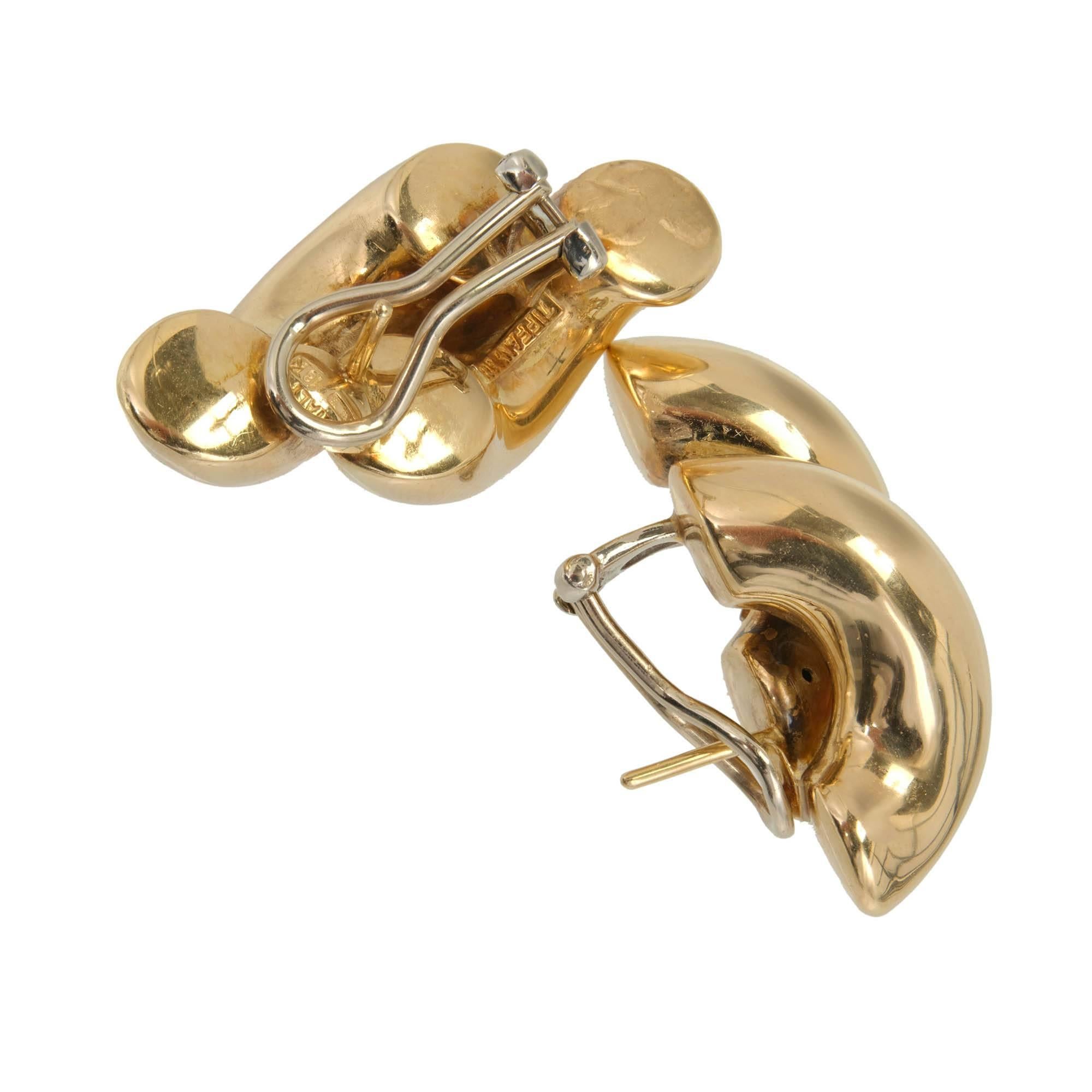 1970's Authentic Tiffany + Co double swirl link 3-D clip post earrings. Made from 18k yellow gold, each earring features a graceful double swirl link design, exuding a sense of fluidity and movement. The clip post closure ensures a secure and