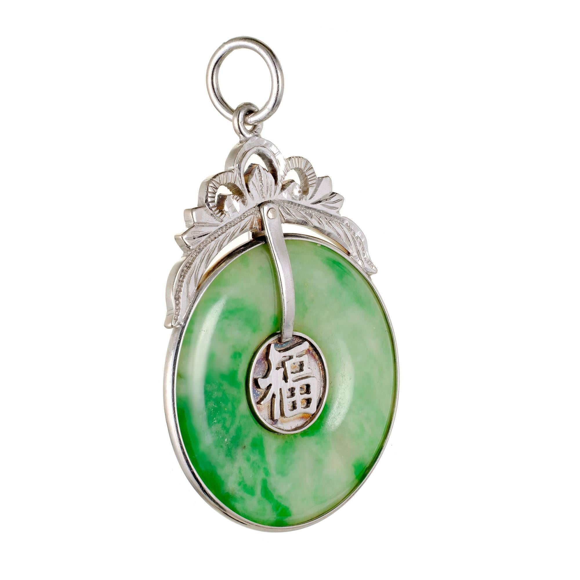 Round natural bright mottled green Jadeite Jade Hololith pendant with a 14k white gold frame and top. Hand engraved and GIA certified.

1 Hololith mottled green Jadeite Jade, 25.77 x 25.73 x 2.73mm, GIA certificate #2181636976
14k white gold
Top to