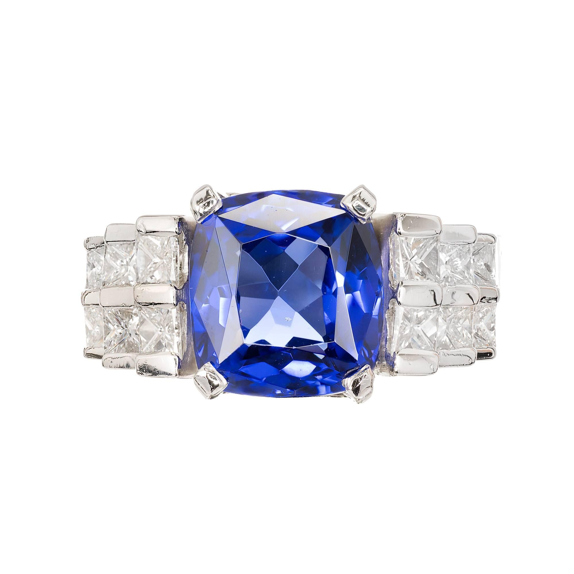 Vivid purple-blue tanzanite with princess cut accent diamonds. Heavy solid platinum engagement setting made just for this stone. 

1 cushion cut Tanzanite 6.38cts.
12 princess cut diamonds 1.50cts, F, VS1.
Size 8 ½ and sizable.
Stamped