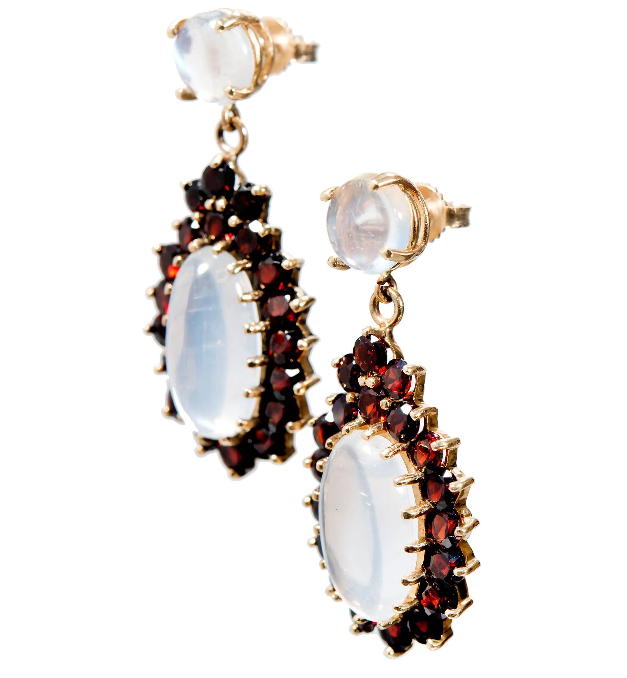 Mid-Century Moonstone and garnet dangle earrings. 2 round round blue hue moonstones and 2 long oval dangle moonstones each with a halo of round garnets. 14k yellow gold.  

36 fine round Garnets 3mm, approx. total weight 4.50cts
2 round Moonstones,