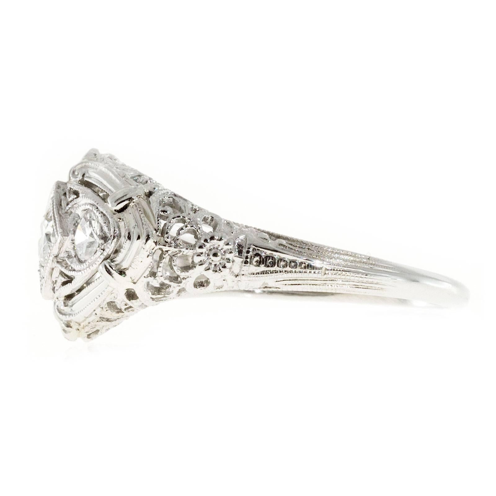 Original 1930's Art Deco pierced filigree engagement ring with 18k white gold base and Platinum diamond top. 

3 round brilliant cut diamonds, approx. total weight .40cts, F, VS1 to VS2
18k white gold and Platinum
Stamped: 18k
Width at top: