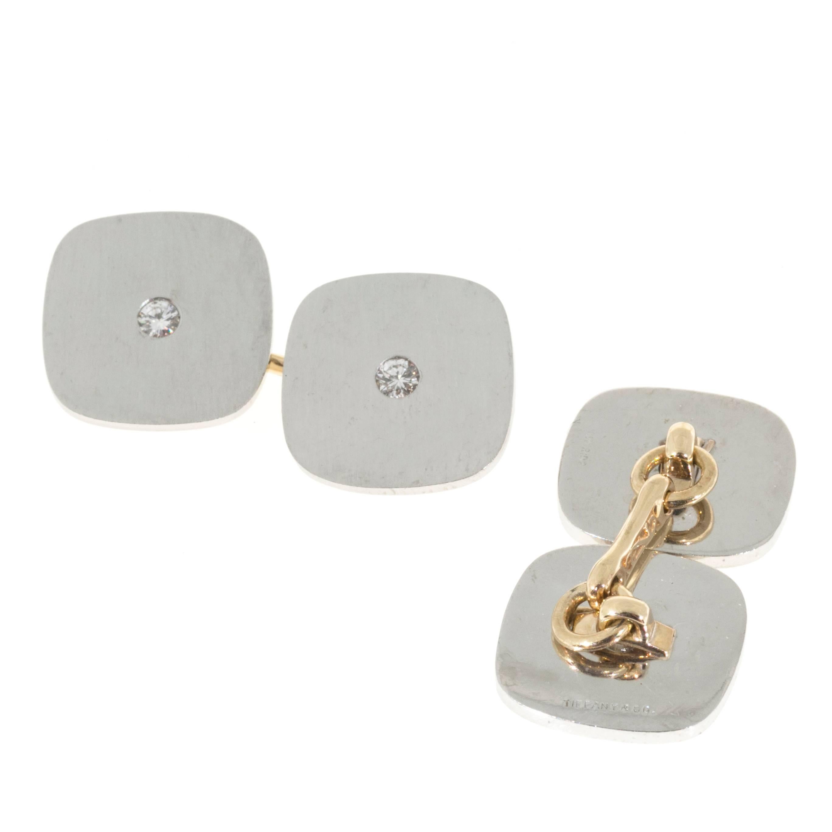 Solid square design Platinum cushion shape double sided Tiffany & Co cufflinks with full cut diamond centers. The cushion shaped Platinum tops measure 13.7 x 1.2mm thick. The cushion shaped tops are connected by a 14k yellow gold bar and jump ring.