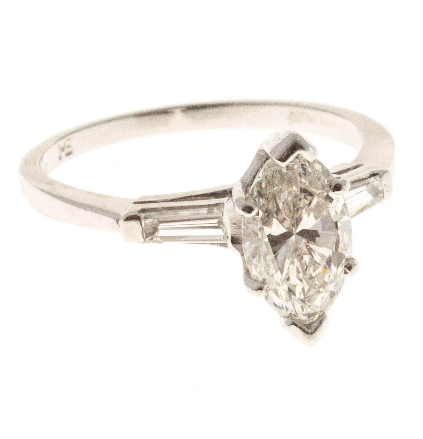 Marquise Ideal cut engagement ring with baguette side diamonds in a platinum setting. 1960-1969. 

1 Ideal Marquise diamond, approx. total weight 1.31cts, H-I, SI1, 10.00 x 5.73 x 3.88mm, 
2 baguette cut diamonds, approx. total weight .10cts, H,