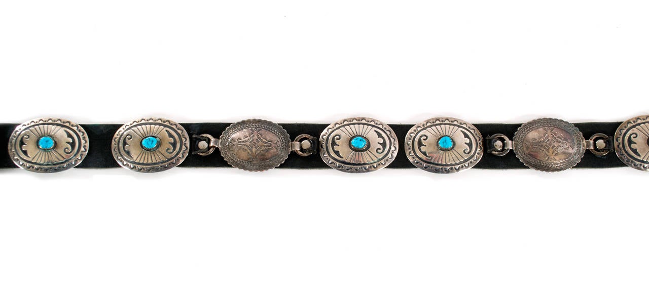 A coin-metal concha belt with eleven wagon-wheel plaques, each inlaid with turquoise and an elaborate buckle with dozens of inlaid turquoise stones.