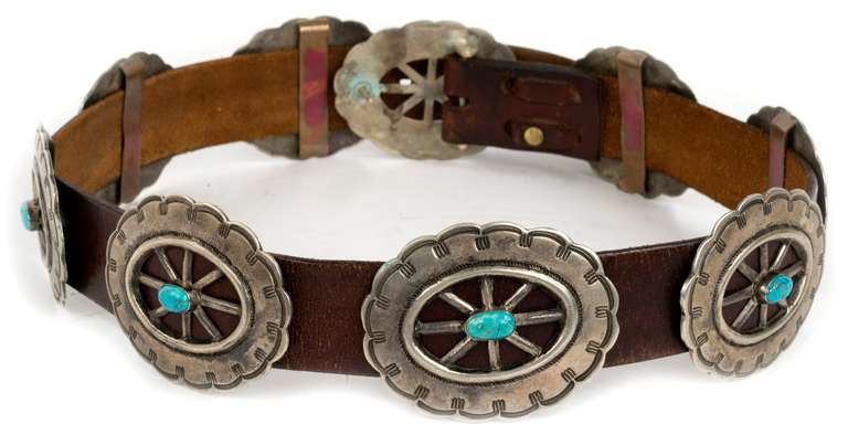 Each of the nine medallions, is carefully hammered, chased, and centered with a bright turquoise stone. They are held together with a 1 1/2-in. thick brown leather belt.
