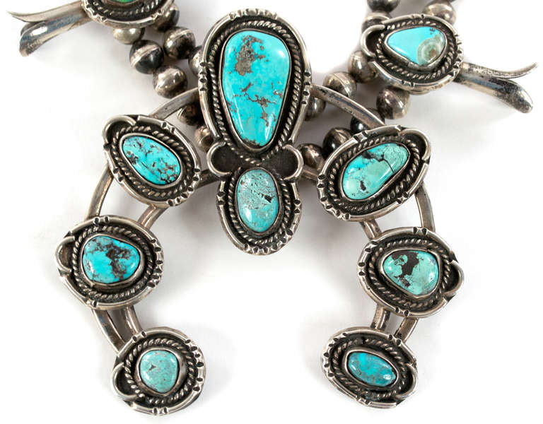 A large silver and turquoise squash blossom necklace with beautiful hand chasing and in pristine condition.