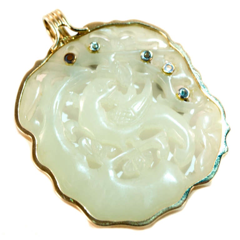 A Chinese white serpentine pendant with gold surrounds and loop for necklace, inlaid with five diamonds.