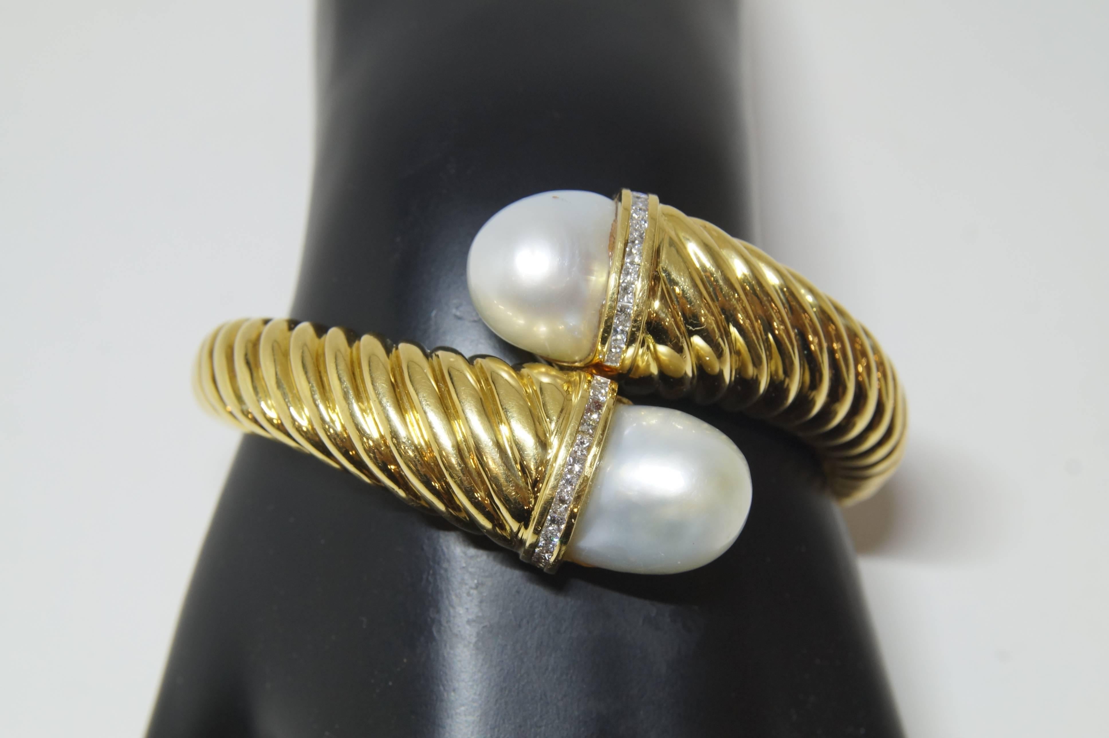 This 18k Yellow Gold fluted bangle bracelet features square diamonds weighing 1.00 ct and 2 Baroque South Sea pearls. 