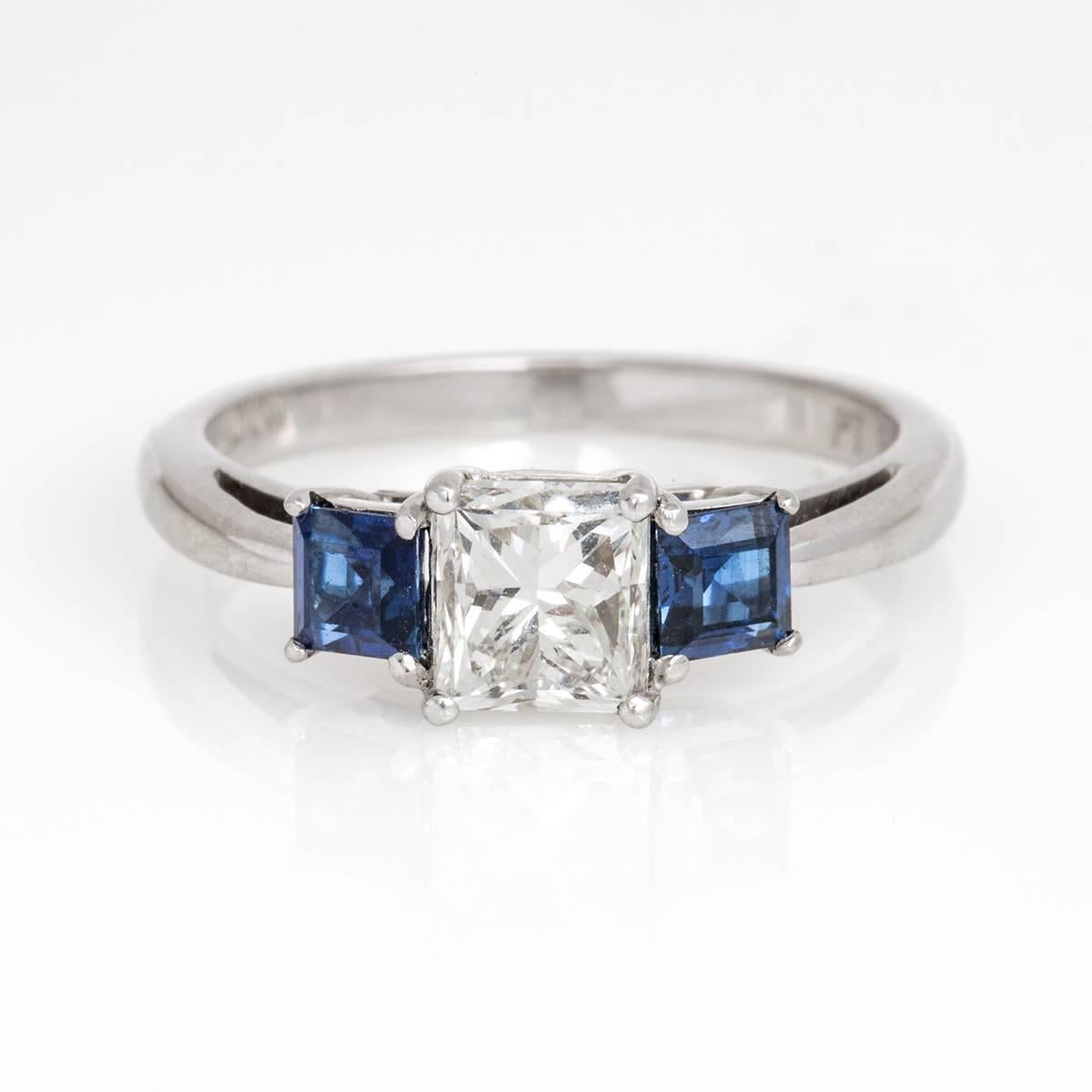 Platinum engagement ring with princess cut diamond weighing a total of 1.00 carat and featuring an F color, SI1 clarity. Two blue sapphires .55 carats total weight. 
GIA Cerified #7116210940. Size 6 