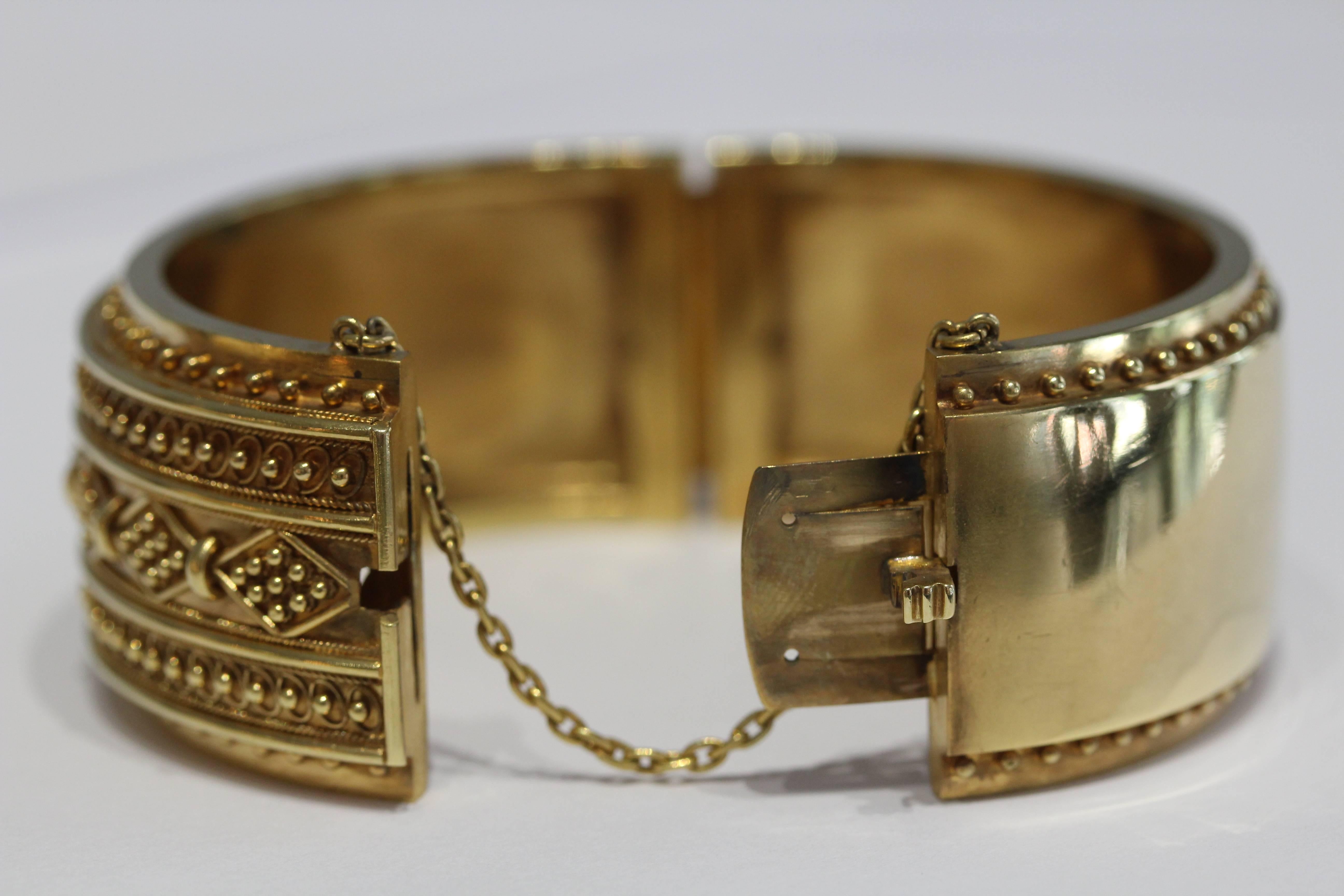 15 Karat yellow gold hinged bangle with granulation design. The bangle
is 25 millimeters wide. English Circa 1890's