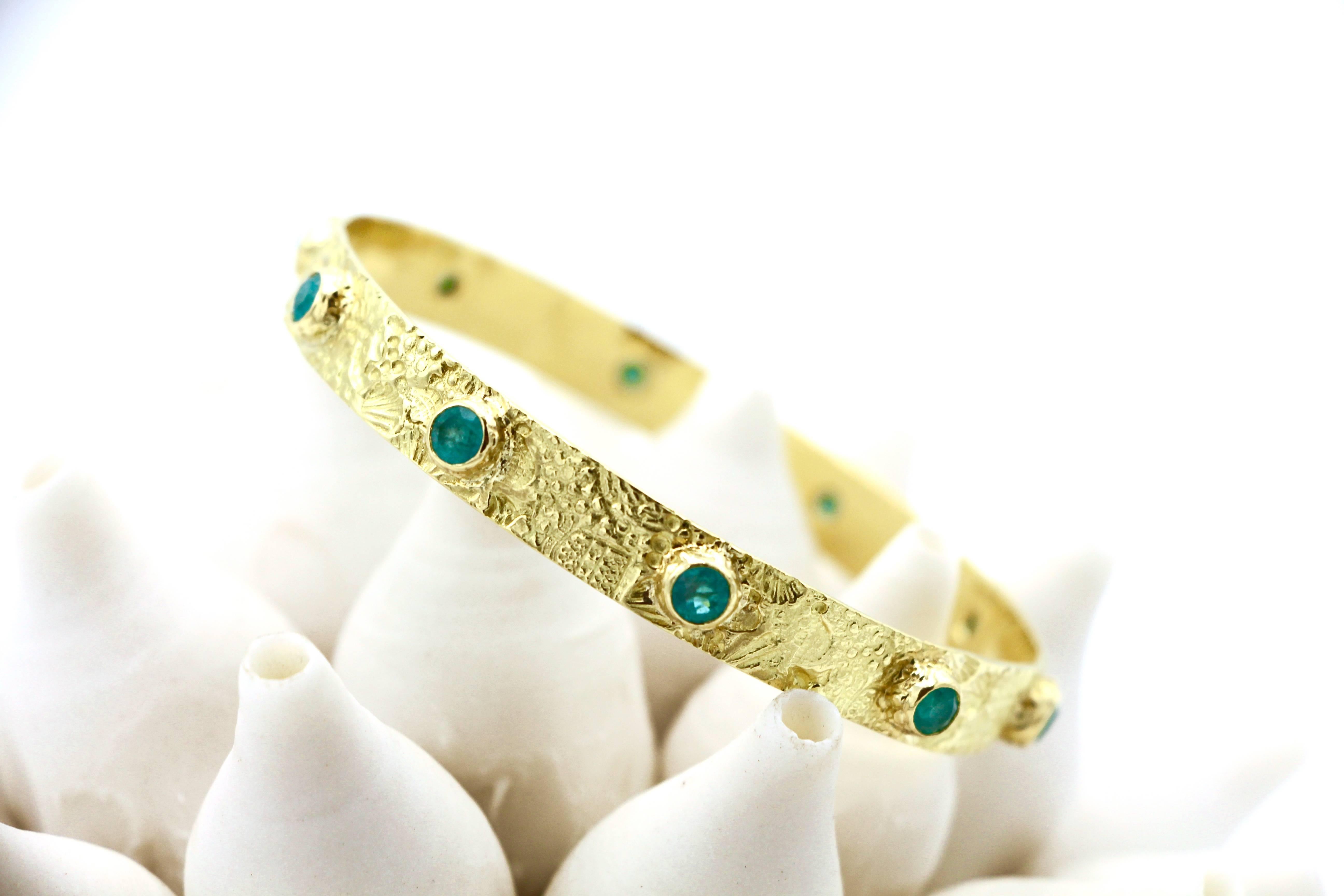 These rare, blue-green 4.68ct Brazilian Paraiba Tourmalines shine like tropical waters lapping onto an 18kt Gold beach of scattered shells and sand in this one-of-a-kind bangle.

